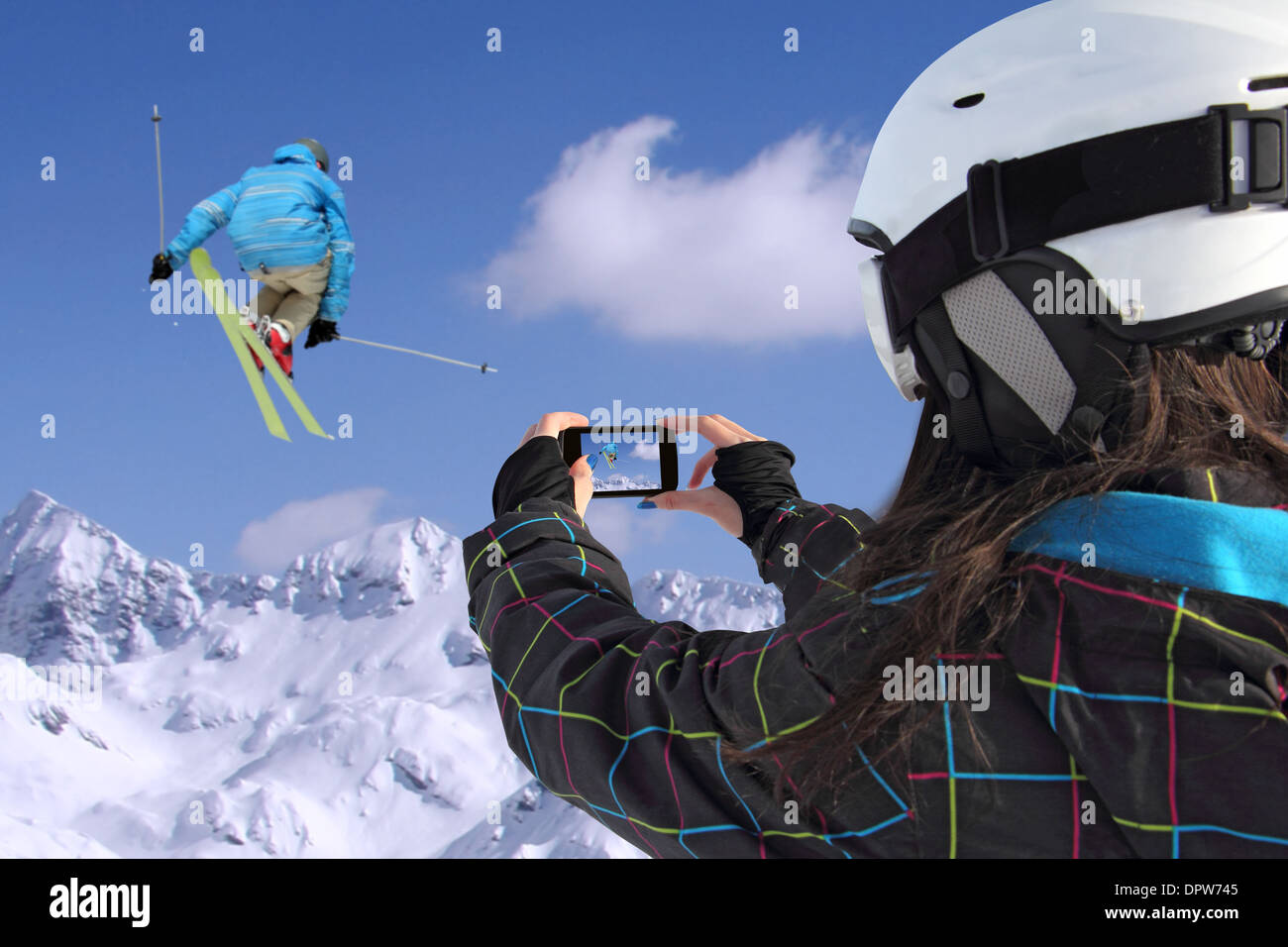 Ein junges Mädchen mit dem Handy Fotos von Skifahrern springen Stockfoto