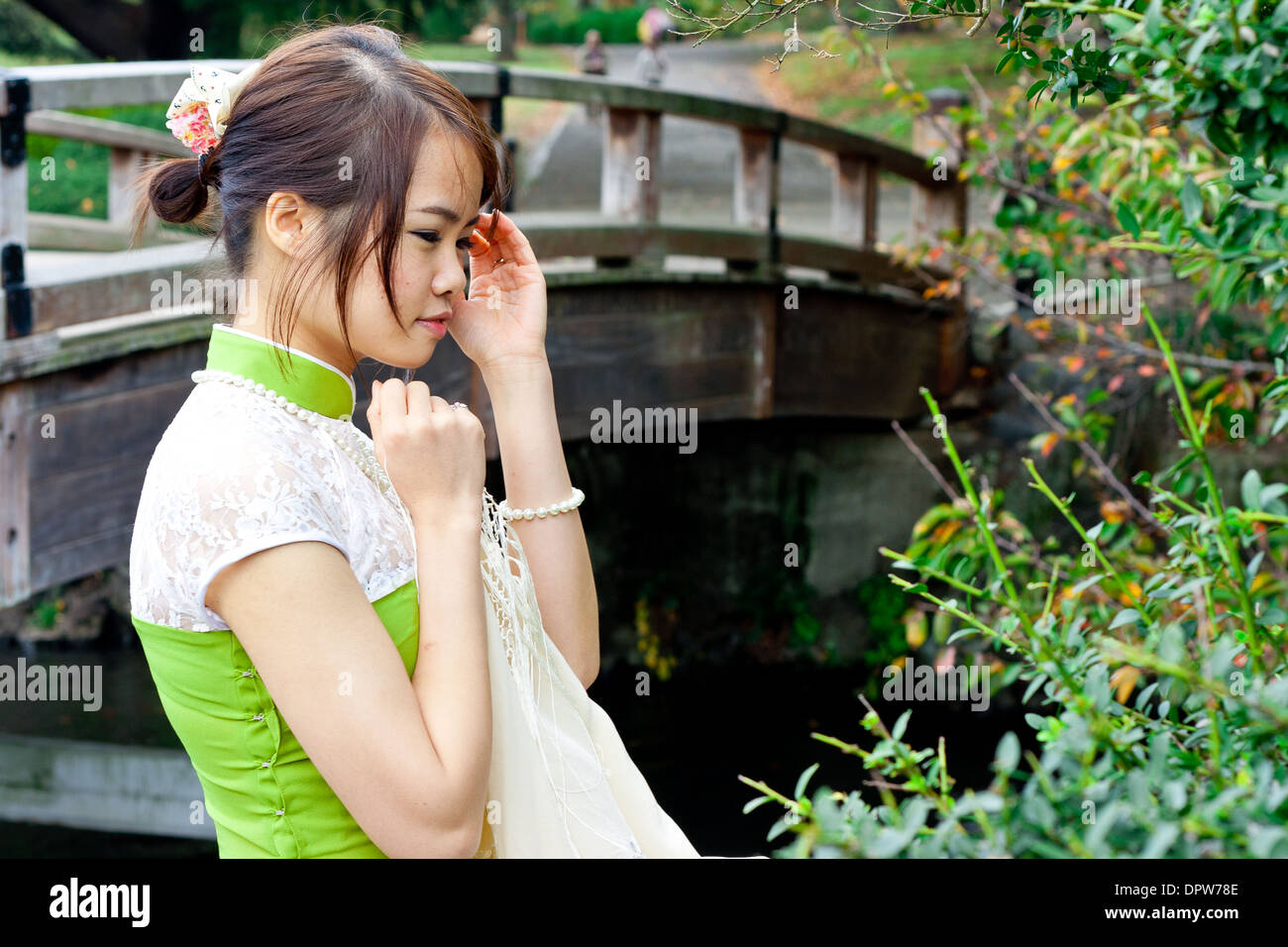Junge Frau in Traditioneller vietnamesischer Kleidung, Die Auf Die Zweigstelle Blickt Stockfoto
