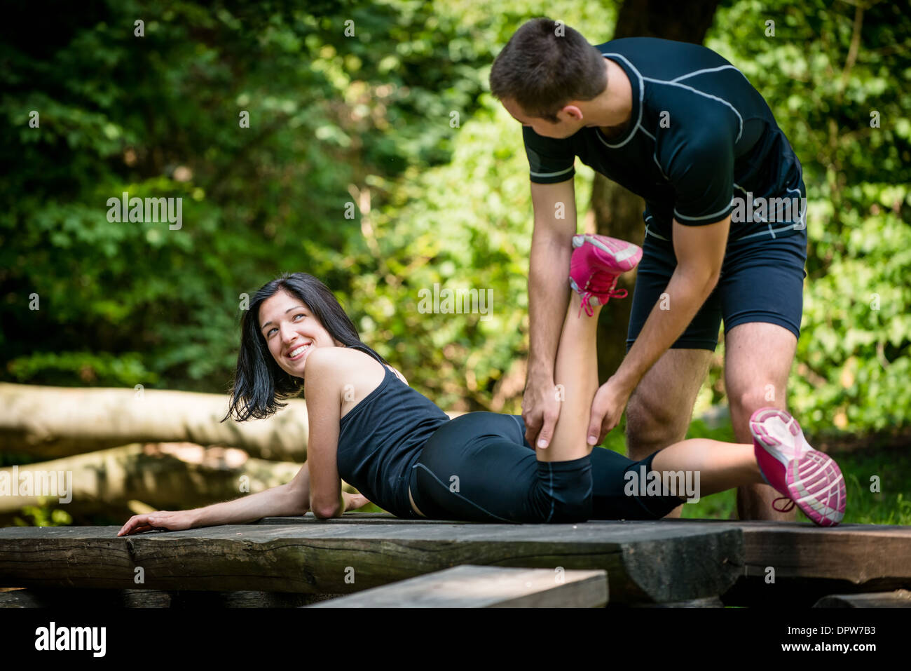 Entspannen Sie nach dem Sport - Mann massiert Kalb seines Freundes outdoor - Frau liegt auf Bank Stockfoto