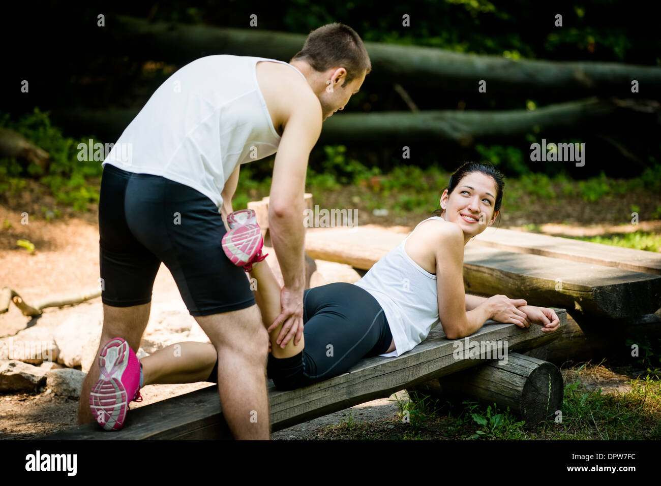 Mann gibt Massage des Kalbes, junge Frau nach dem Joggen Stockfoto