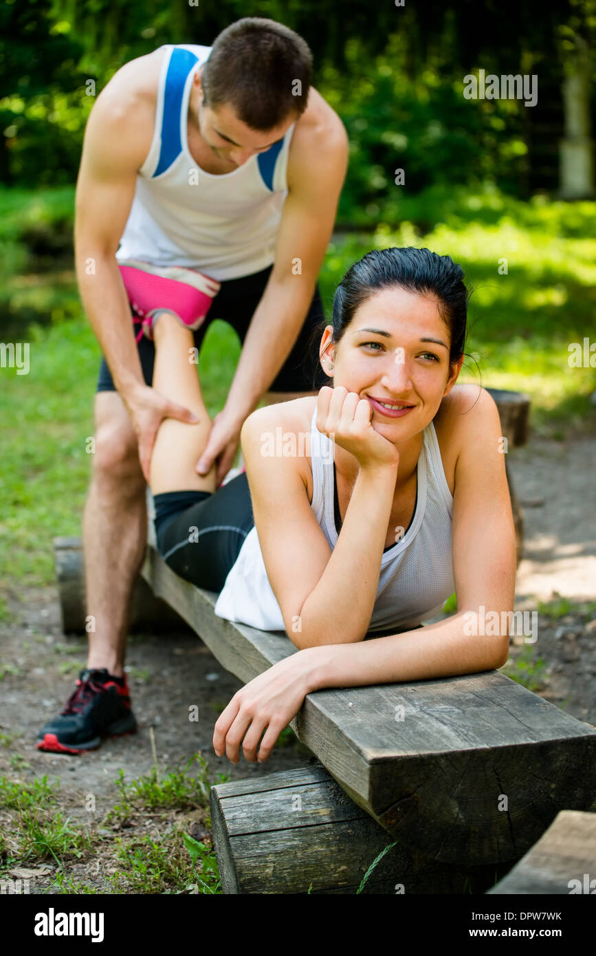 Mann gibt Massage des Kalbes, junge Frau nach dem Joggen Stockfoto
