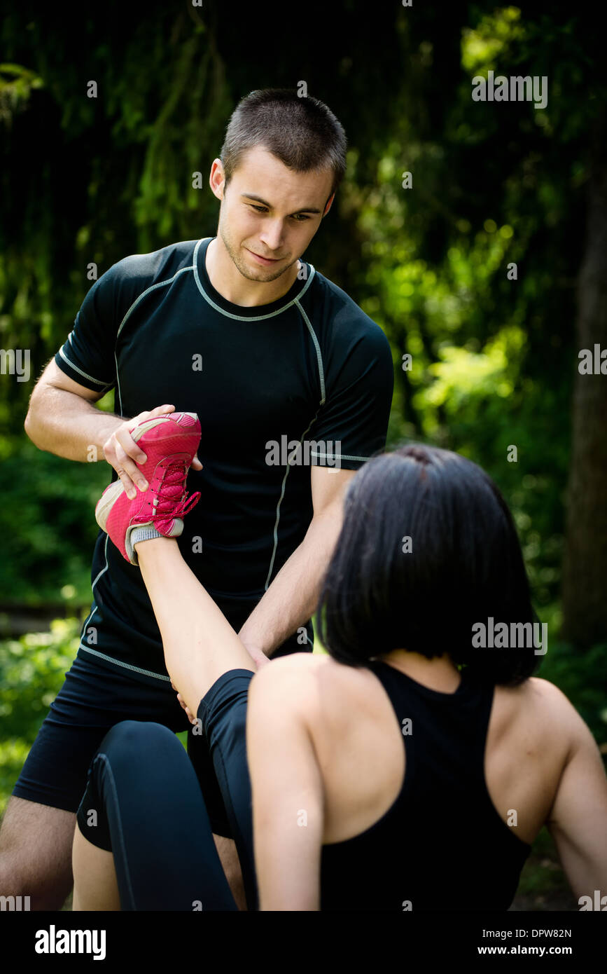 Mann trägt Frau mit Muskel Spasm - Dehnung Bein Stockfoto