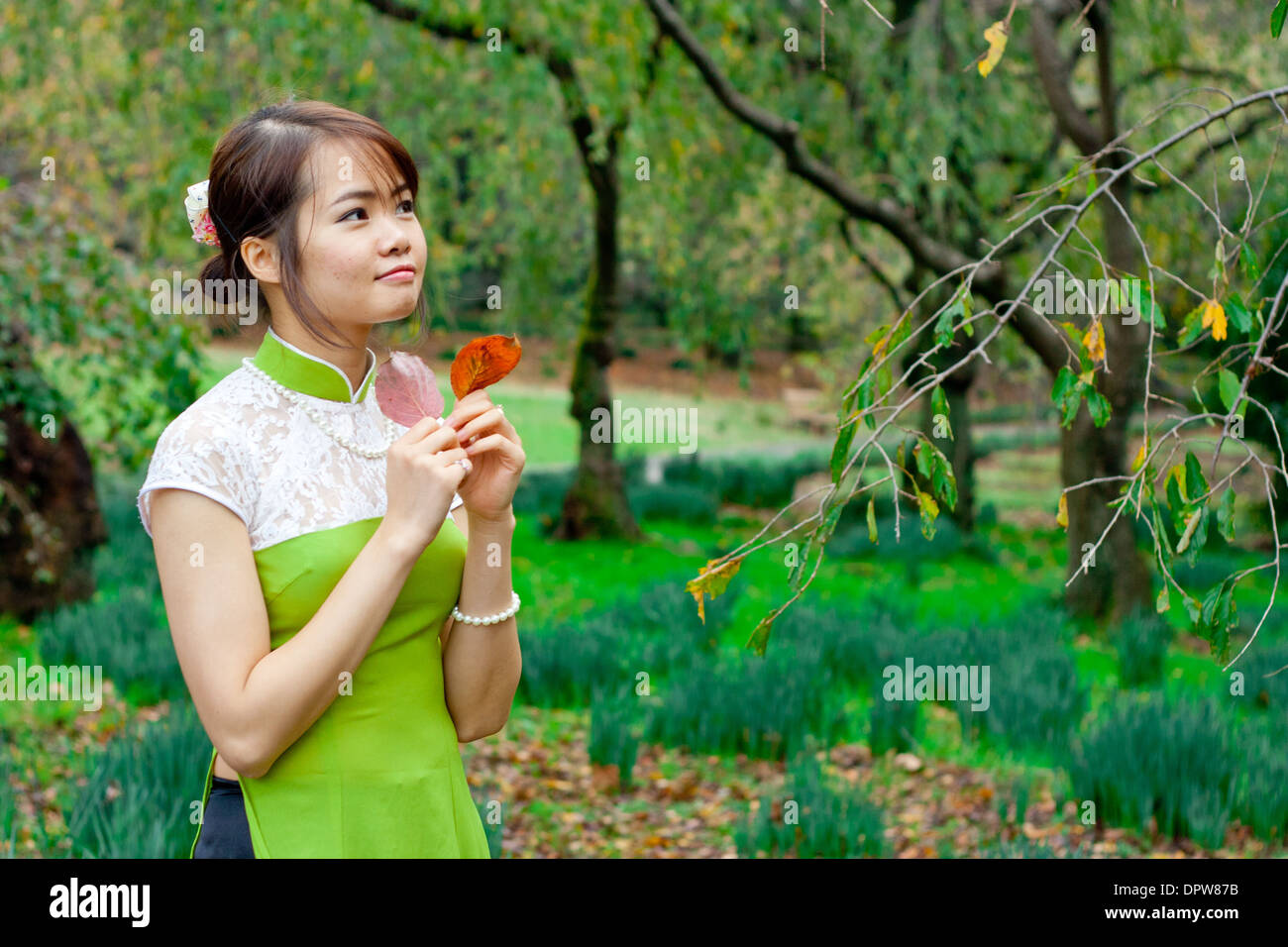 Junge Frau, die Blätter mit einem Wunschausdruck hält Stockfoto
