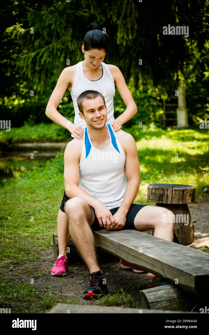 Junge Frau massiert Shouders ihrer Freundin nach dem Sport Training in der Natur Stockfoto