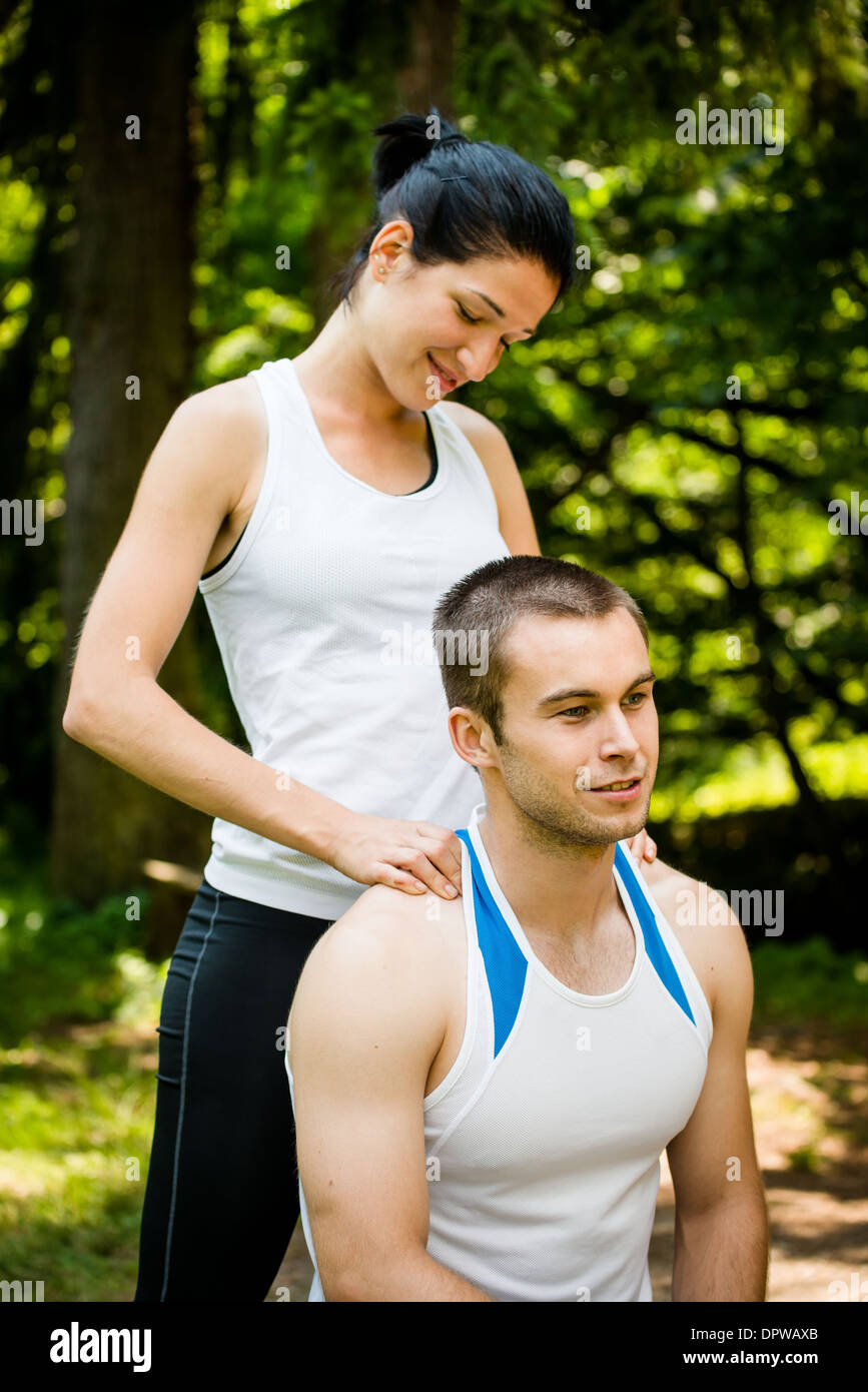 Junge Frau massiert ihre Freundin nach dem Sport Training in der Natur Stockfoto