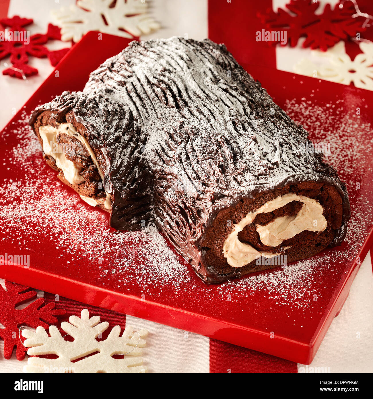 Yule Log Schokolade Schwamm Vanille Creme traditionelle rote Weihnachtsteller Puderzucker bestäuben Snow Flake Dekoration Stockfoto
