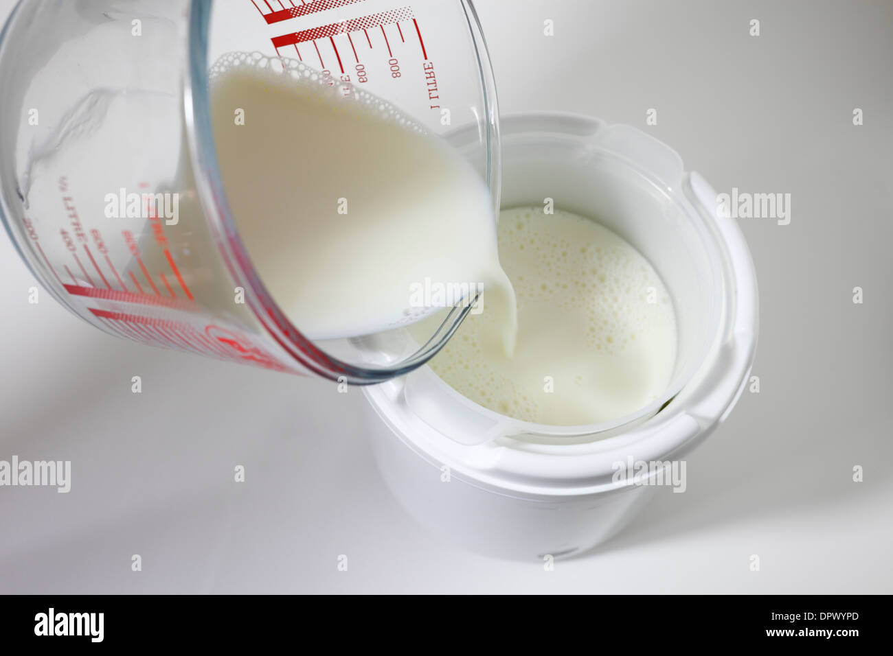 Ein Joghurtbereiter Milch hinzufügen. Stockfoto