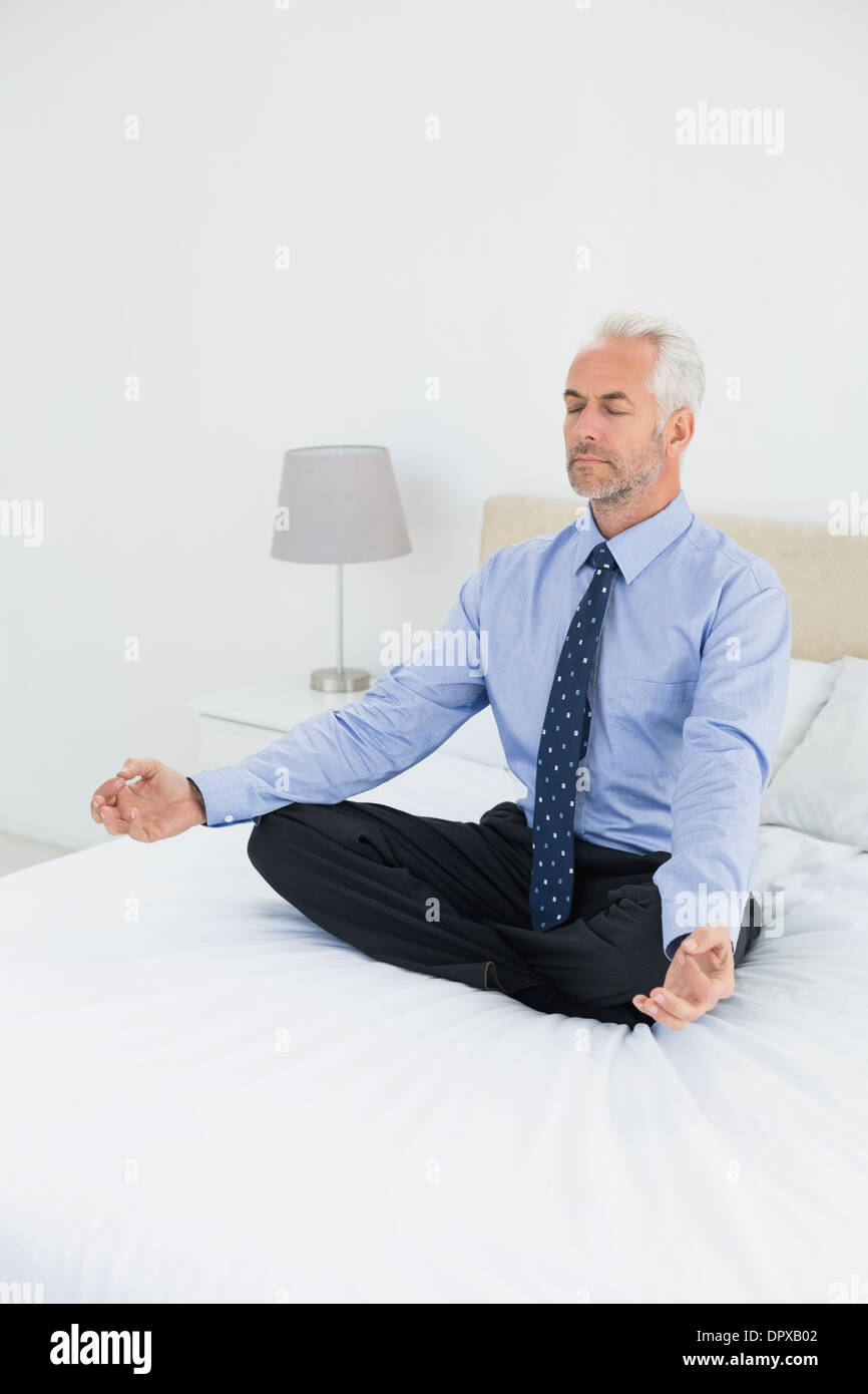 Entspannte reifer Geschäftsmann in Lotus Haltung am Bett sitzen Stockfoto