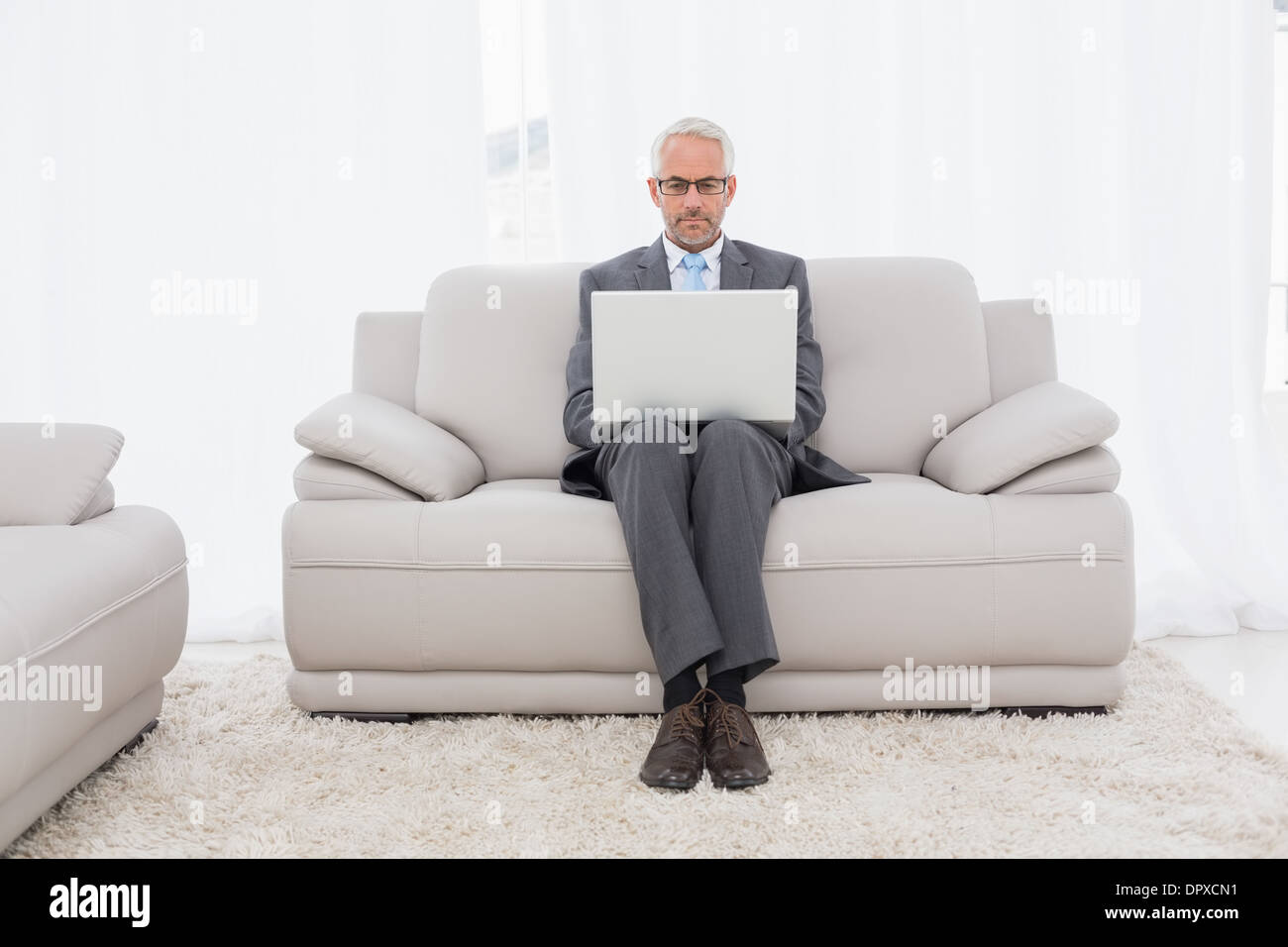 Konzentrierte Geschäftsmann mit Laptop auf dem Sofa im Wohnzimmer Stockfoto