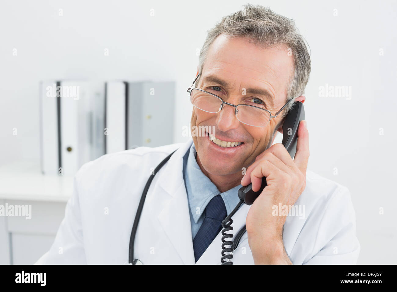 Lächelnde männlichen Arzt mit Telefon im Büro Stockfoto