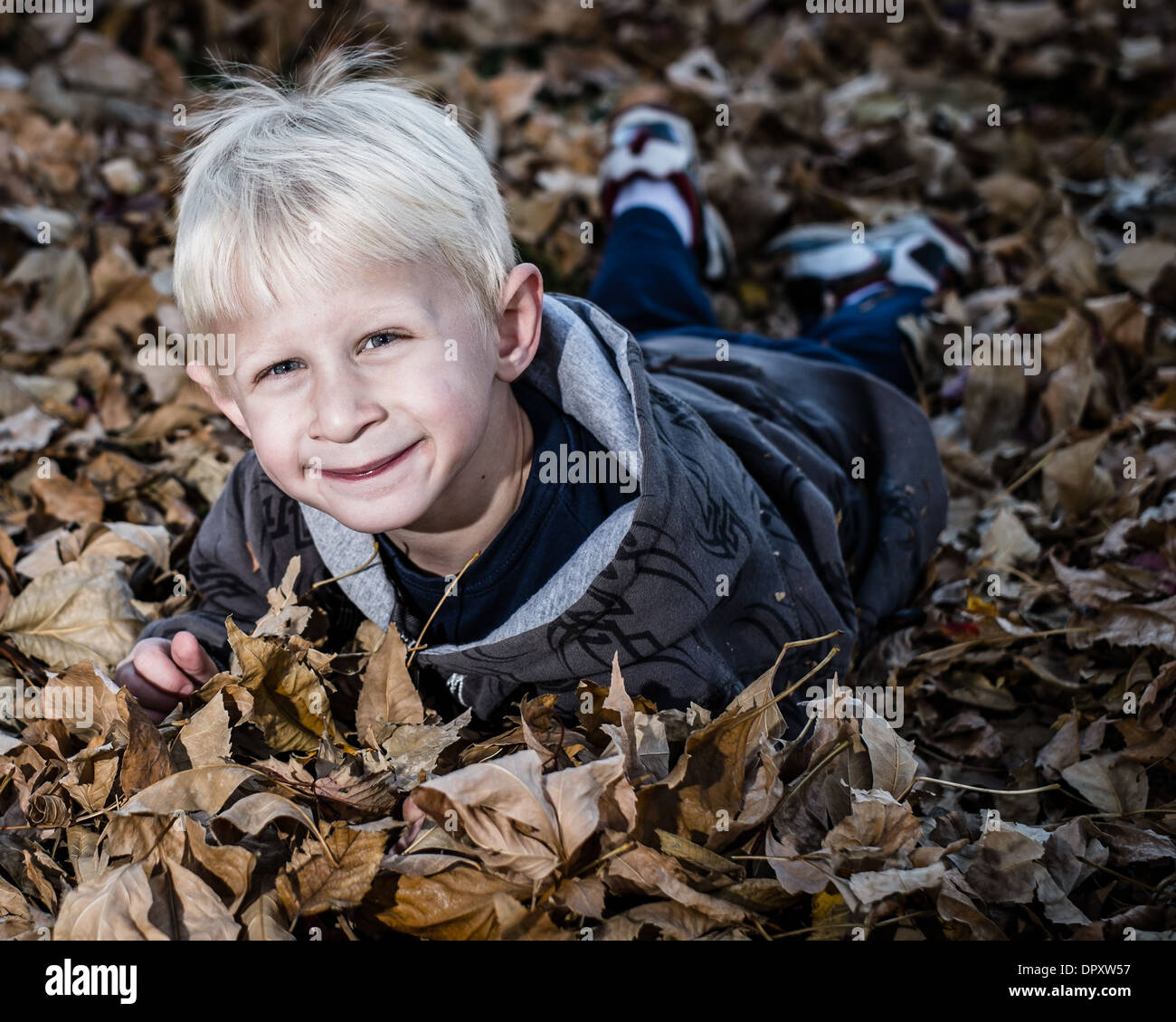 Jungen spielen mit Blättern Stockfoto