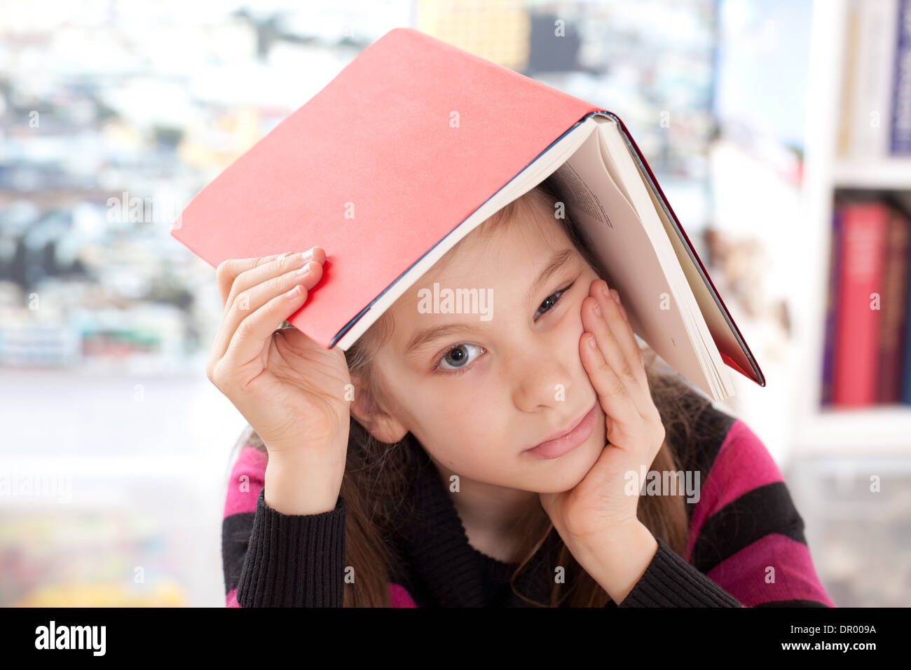 Mädchen mit einem Buch auf dem Kopf als Symbol für Überlastung Stockfoto