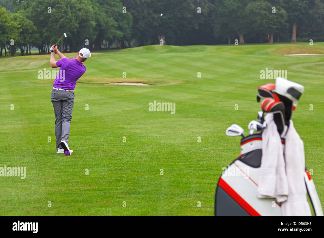 Ein Golfer spielt Mitte Eisen Fairway in grün auf einem Par 4 Loch, Serie 3 geschossen. Schwerpunkt liegt auf den Golfer. Stockfoto