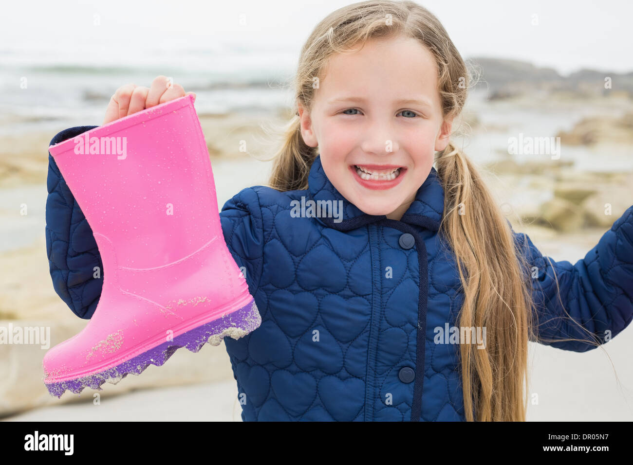 Niedliche Mädchen hält ihre Wellington Boot am Strand Stockfoto