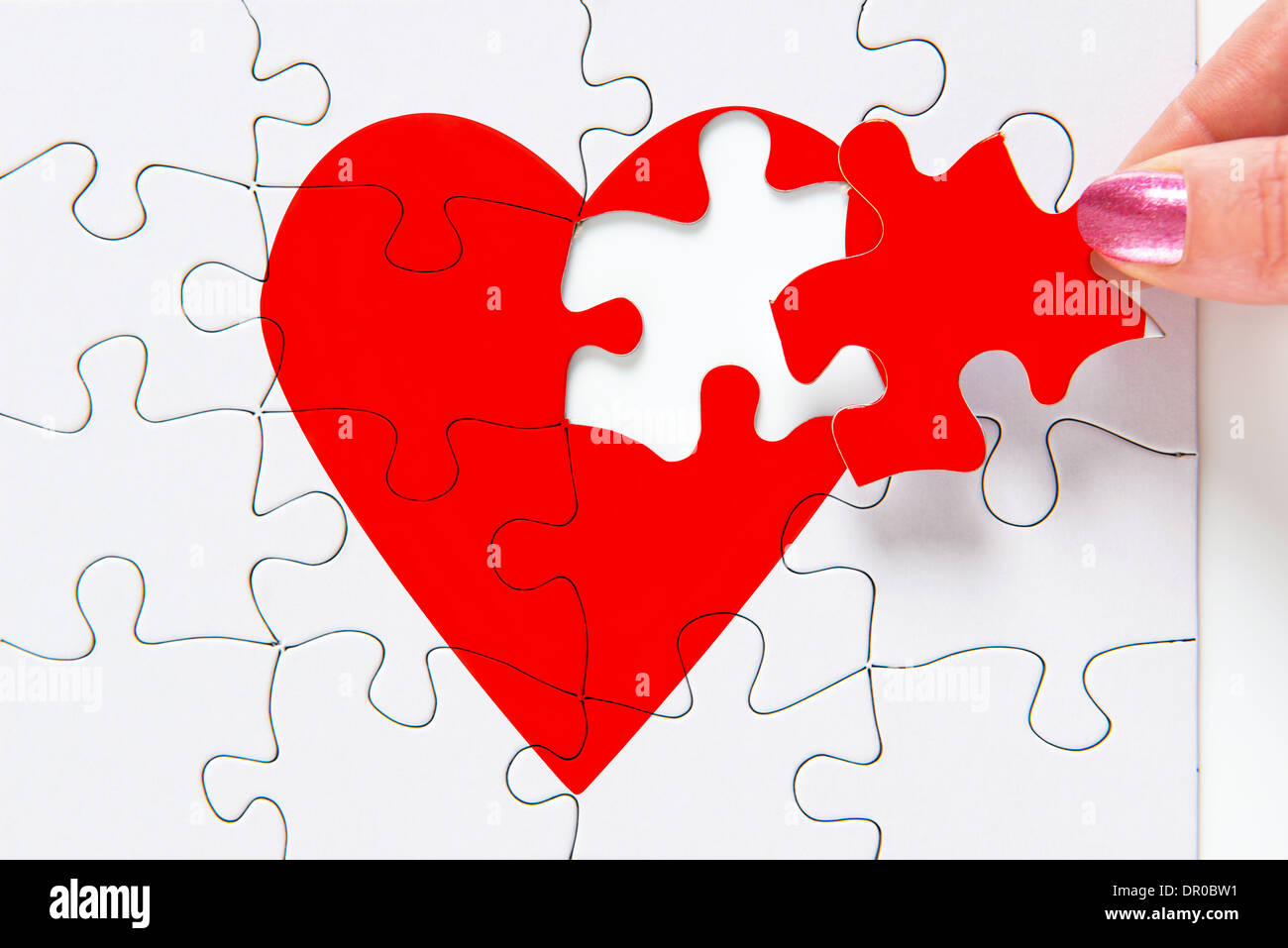 Eine Frau, die Umsetzung des fehlenden Stückes Puzzle rote Herzen Stockfoto