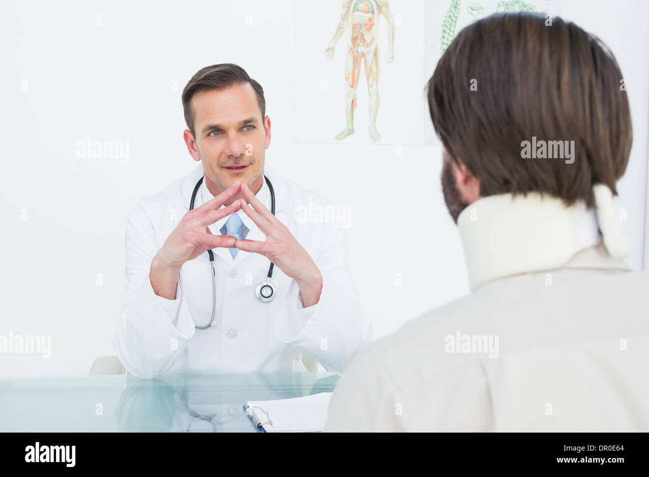 Männlichen Arzt Patienten mit Konzentration am Schreibtisch anhören Stockfoto