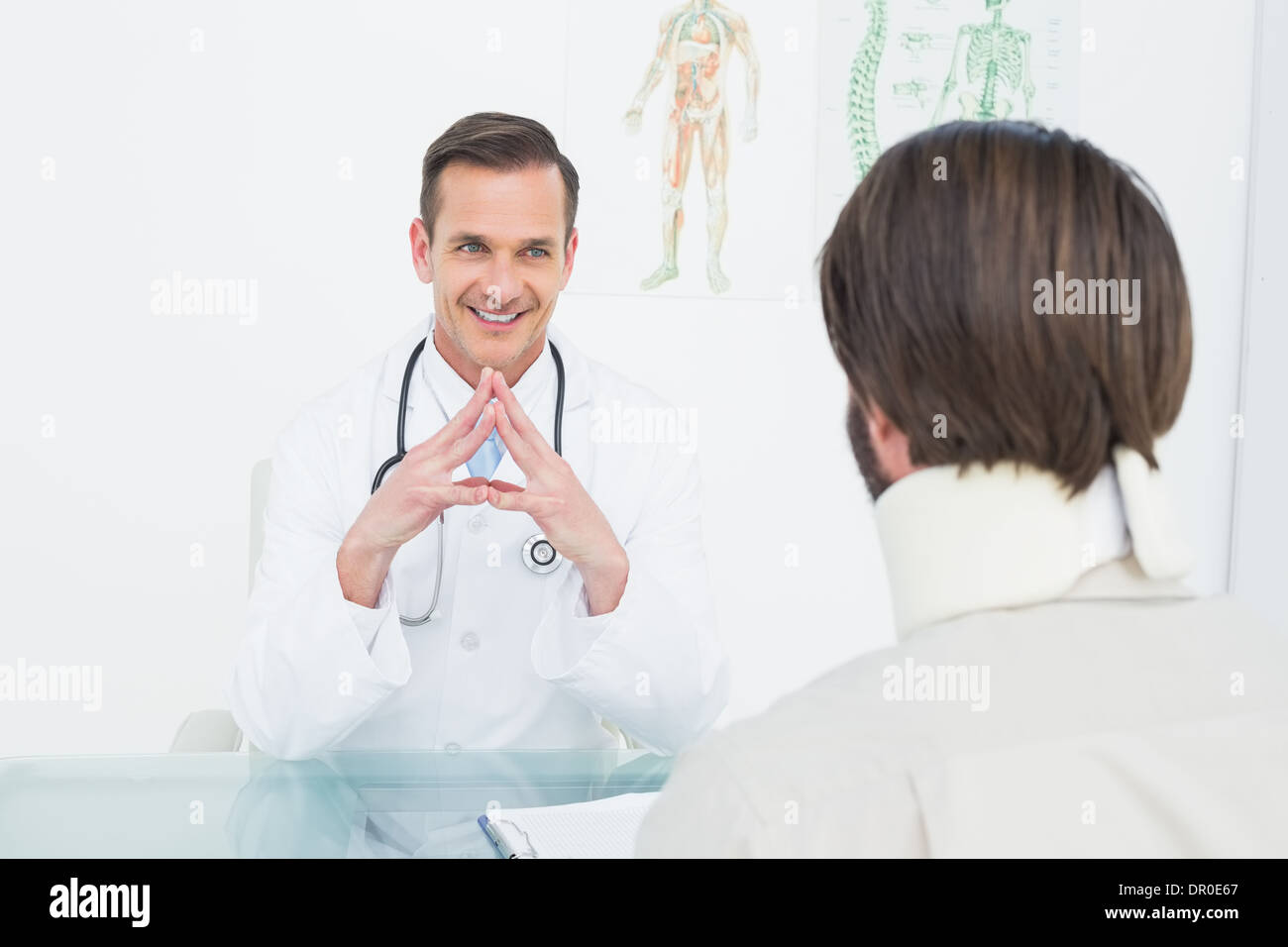 Freundlicher Arzt Patienten mit Konzentration am Schreibtisch anhören Stockfoto