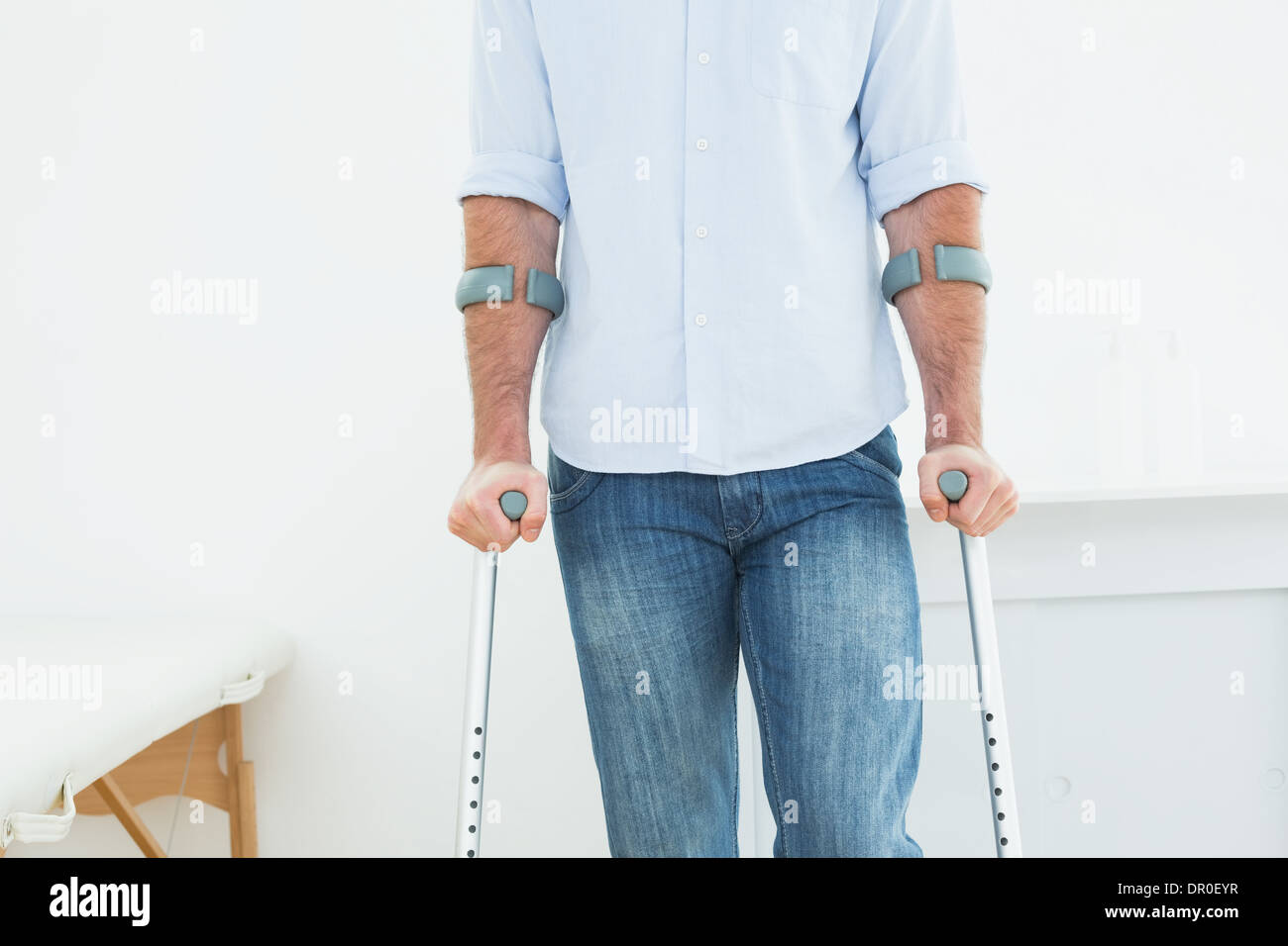 Mittleren Bereich eines Mannes mit Krücken in Arztpraxis Stockfoto