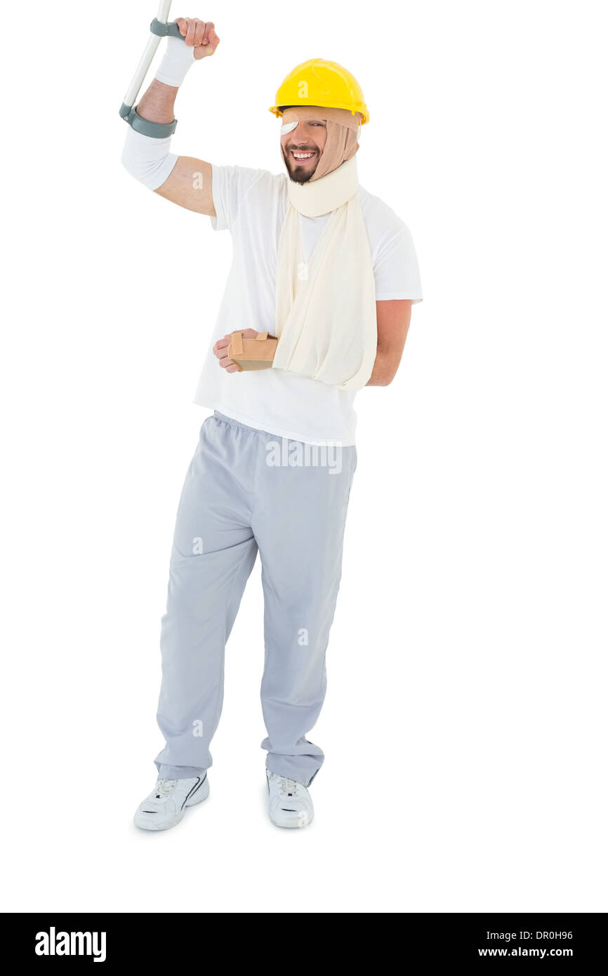 Junger Mann im harten Hut mit gebrochenen Hand und Krücke Stockfoto