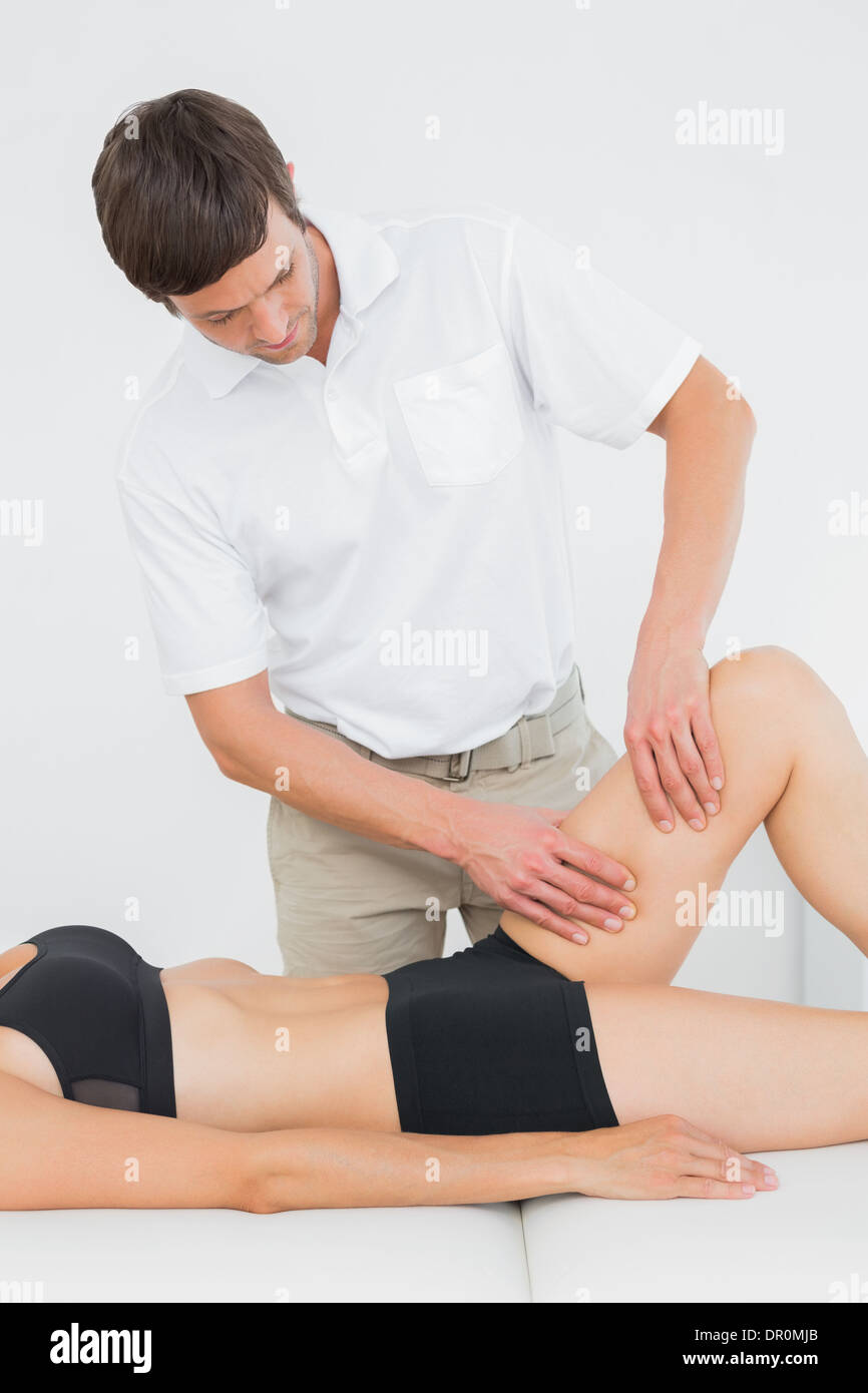 Männliche Physiotherapeut untersucht eine junge Frau Bein Stockfoto