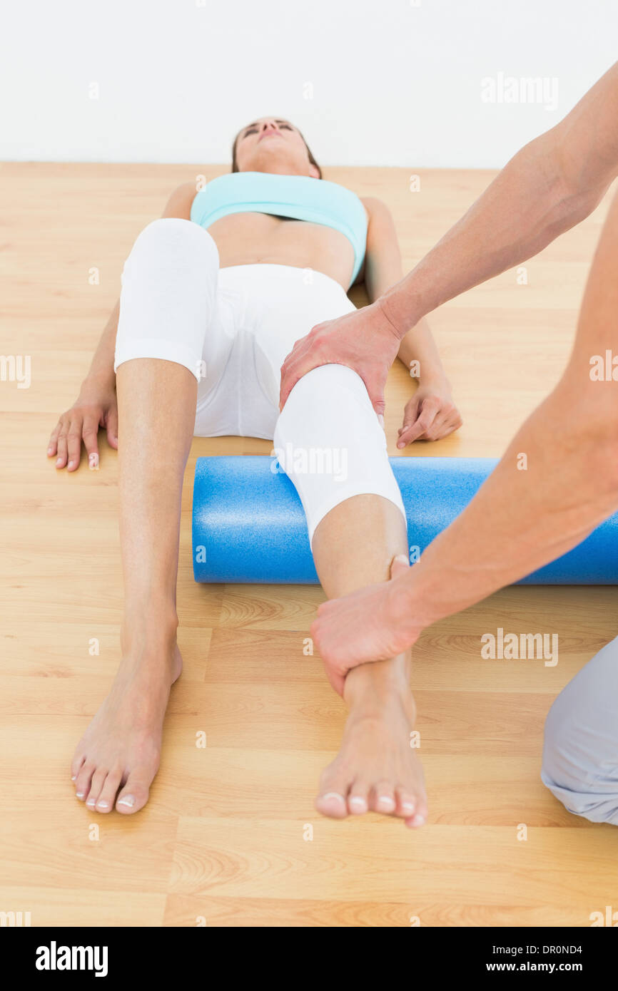 Physiotherapeuten, die eine junge Frau Bein untersuchen Stockfoto