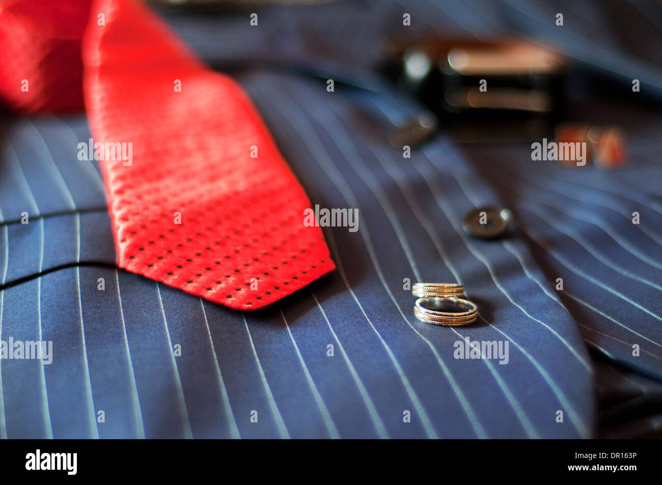 Hochzeit Ringe, liegen rote Krawatte, Gürtel und Manschettenknöpfe, auf eine Hochzeitsanzug des Bräutigams Stockfoto