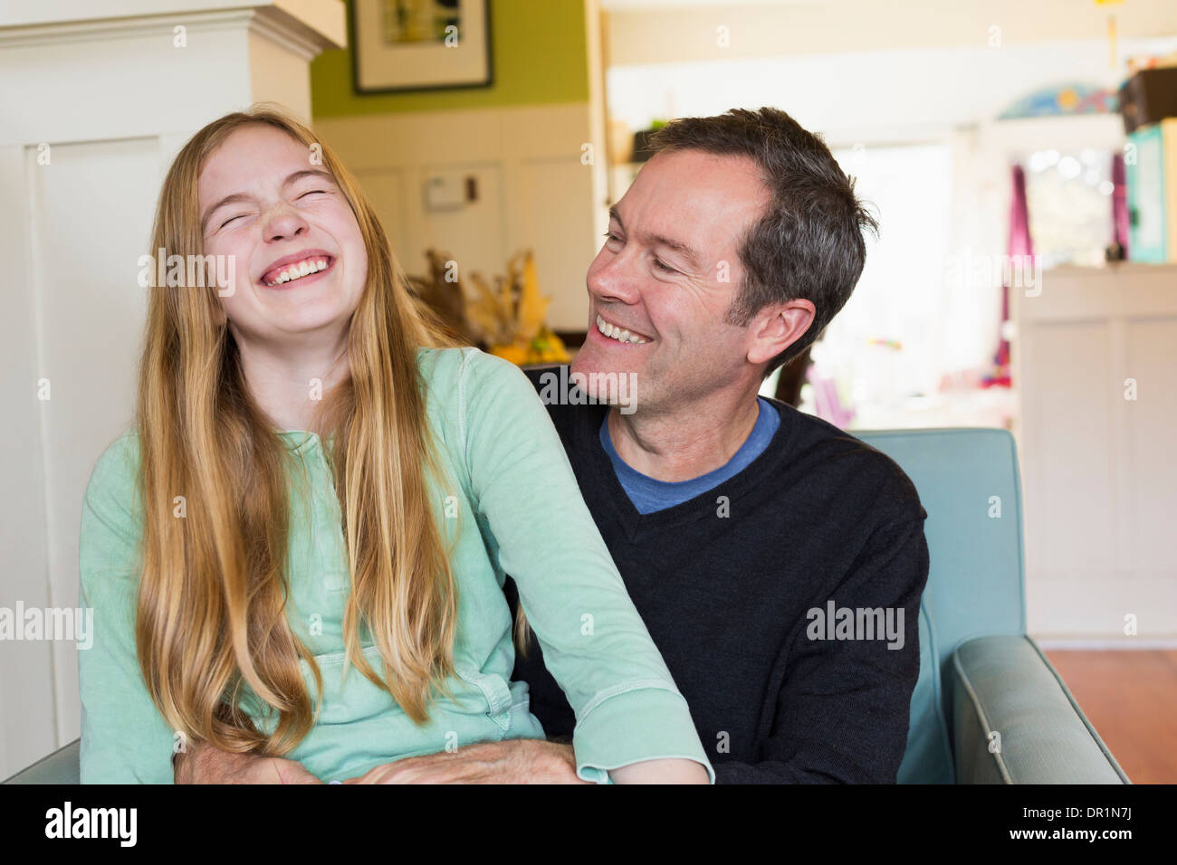 Kaukasische Vater und Tochter lachend im Wohnzimmer Stockfoto