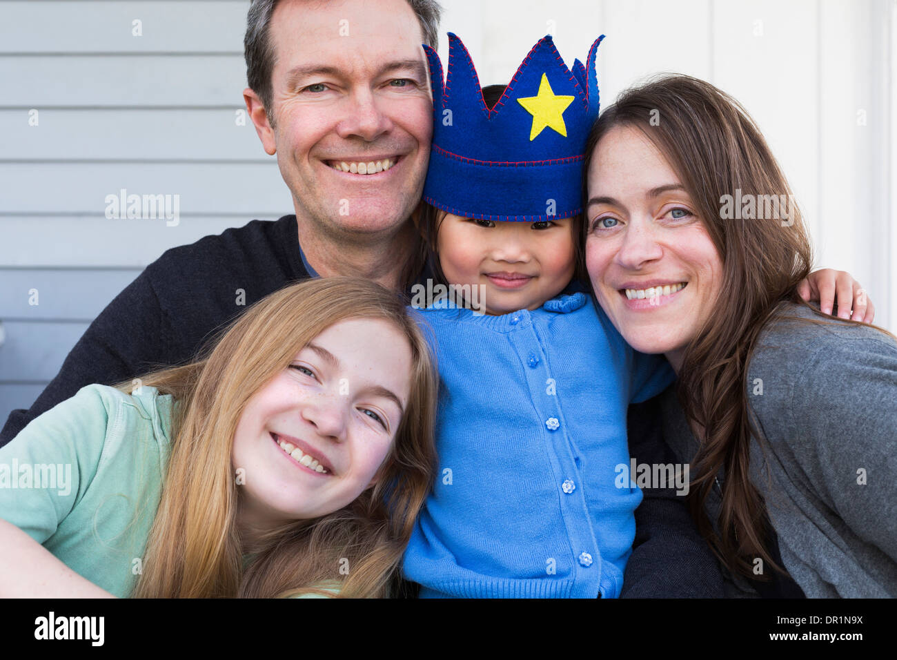 Familie lächelnd zusammen vor Haus Stockfoto