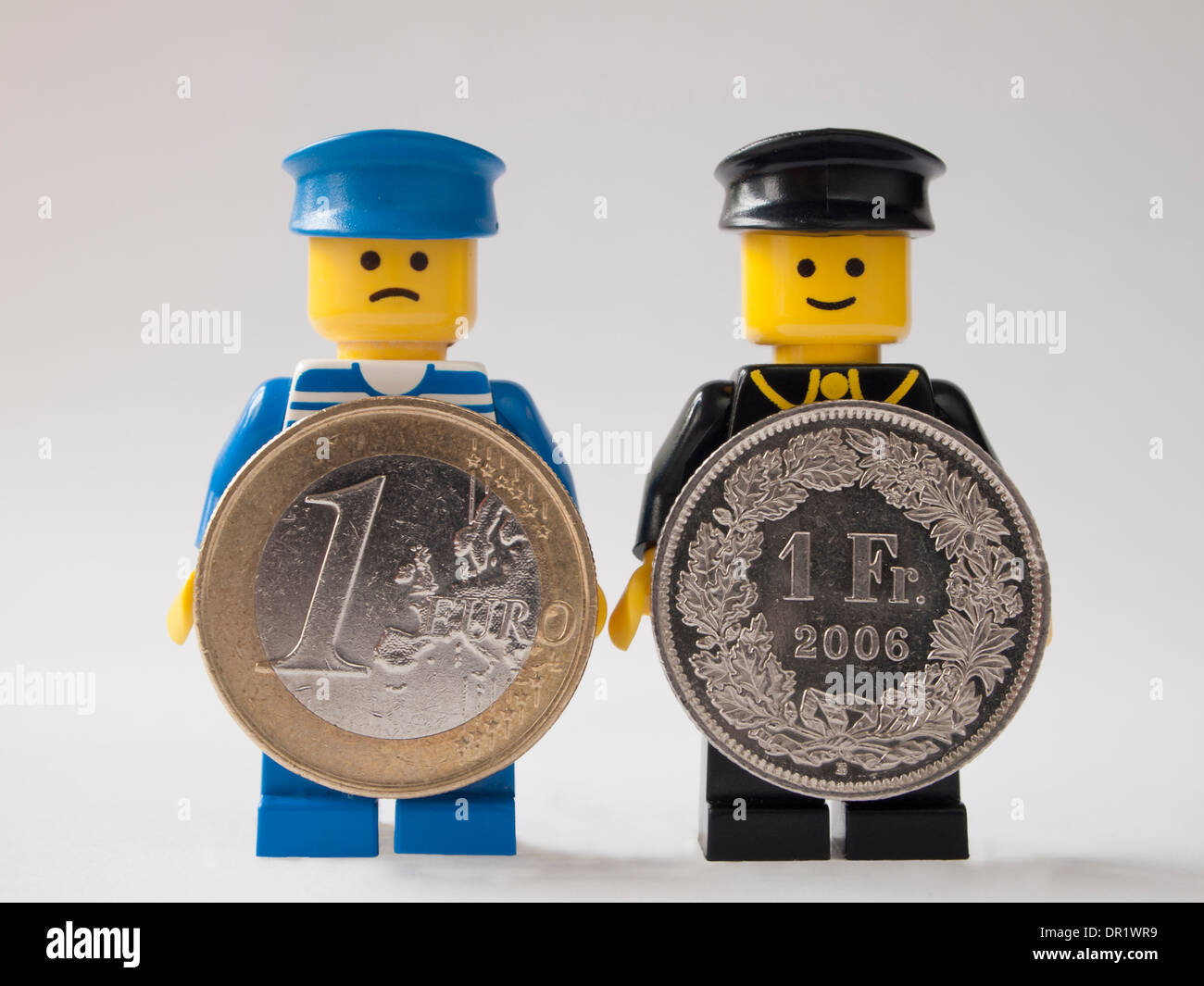 LEGO-Männer halten Euro und Schweizerfranken Münzen Stockfoto