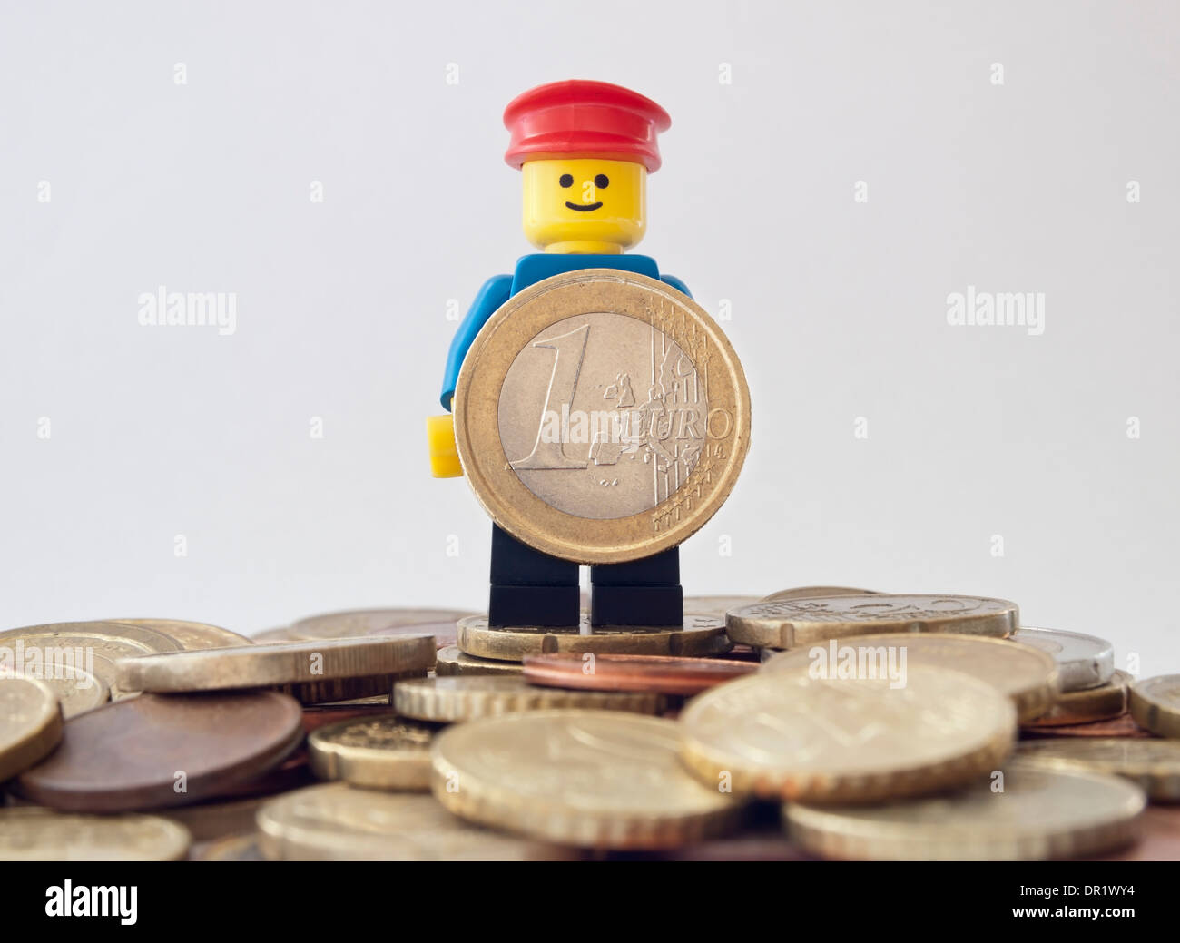 Lächelnder LEGO Mann hält EURO-Münze Stockfoto
