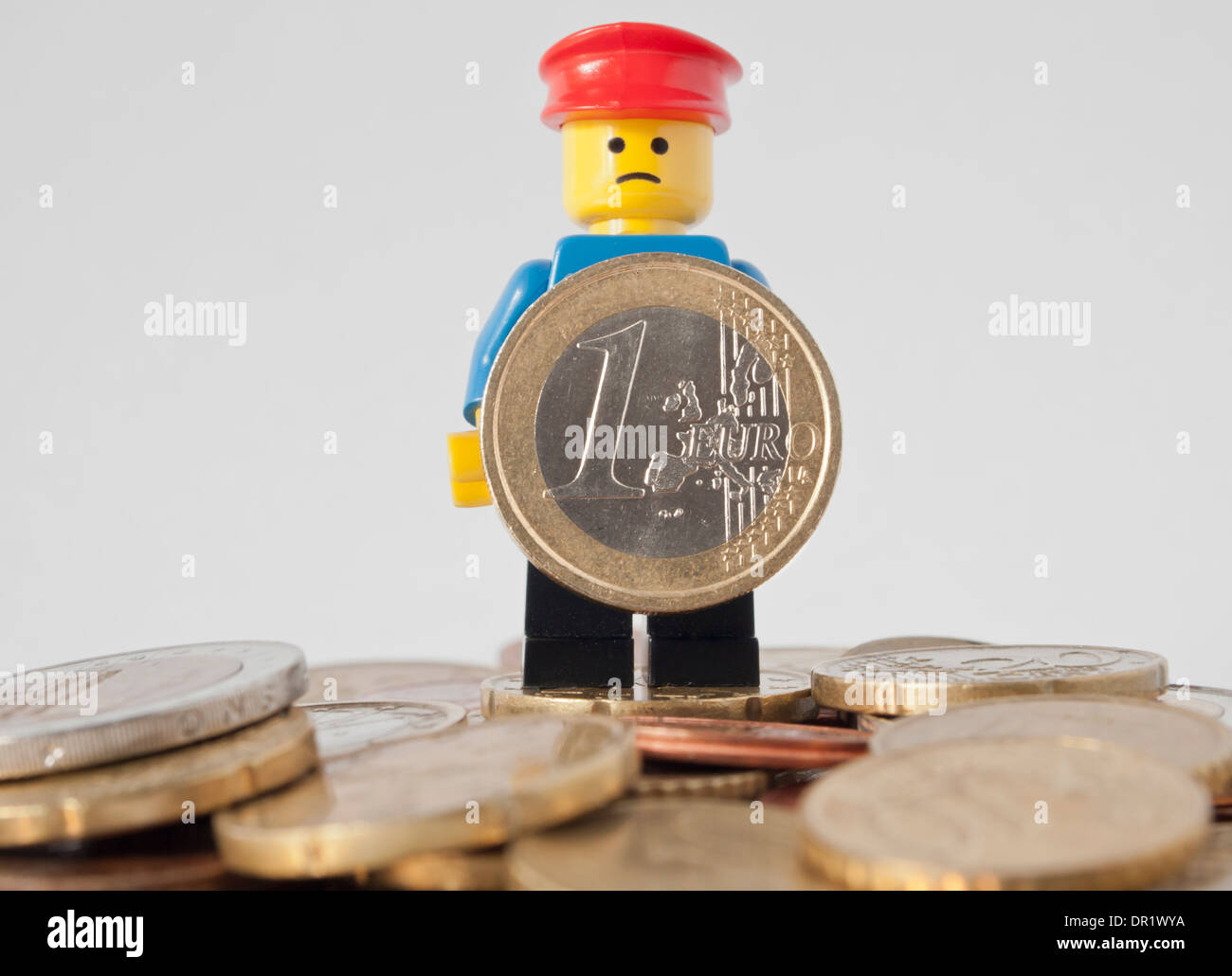 Trauriger LEGO Mann hält EURO-Münze Stockfoto