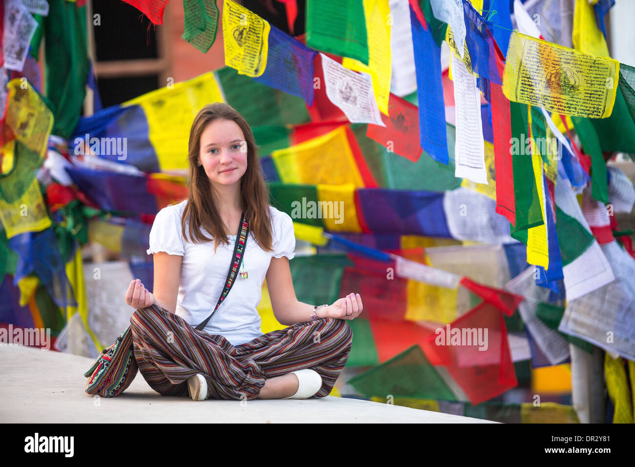 Teengirl sitzen auf buddhistische Stupa, Gebetsfahnen im Hintergrund fliegen. Stockfoto