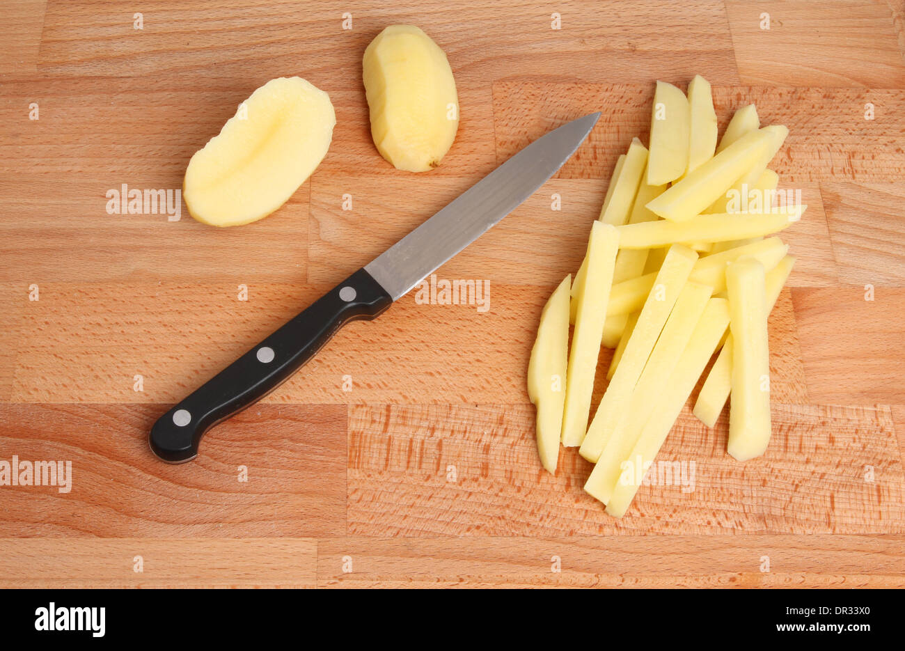 Pommes frites schneiden, Messer und Kartoffel auf einem Holzbrett Stockfoto
