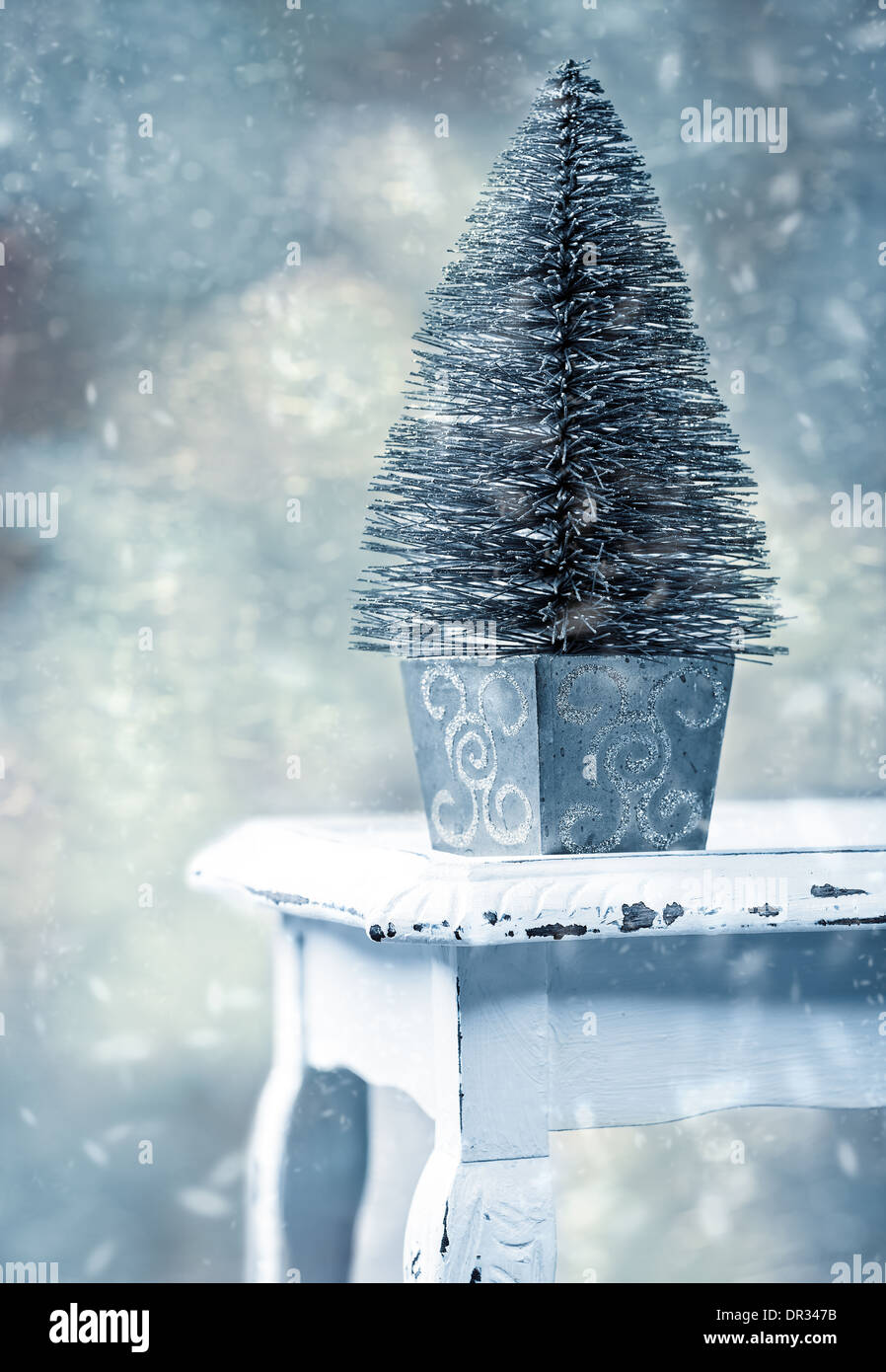 Miniatur-Weihnachtsbaum auf rustikalen Tisch mit fallendem Schnee - Vintage Filterwirkung Stockfoto