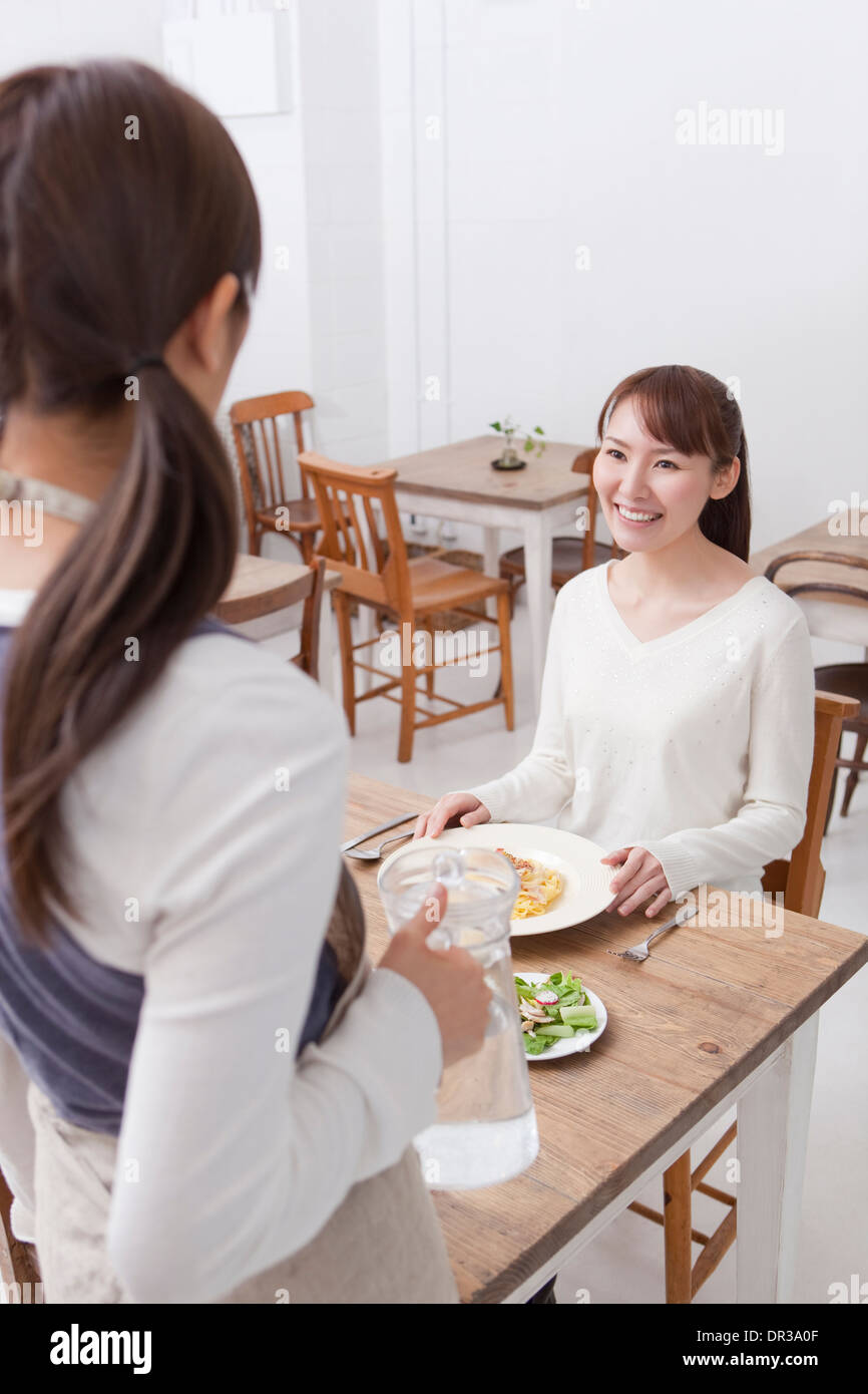 Junge Frau im Café serviert wird Stockfoto