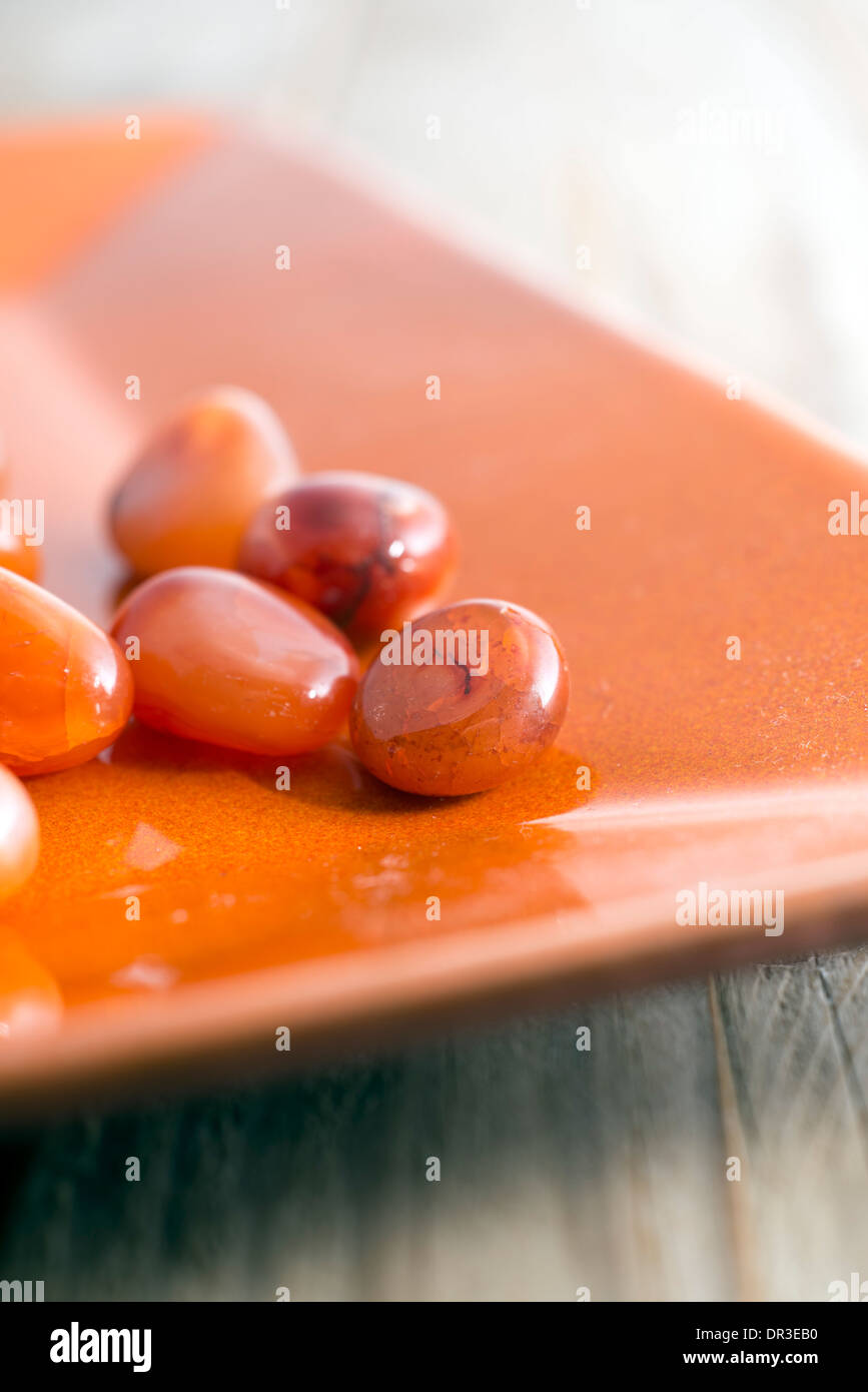 Orange Kieselsteinen in einer Schale aus Steingut Stockfoto