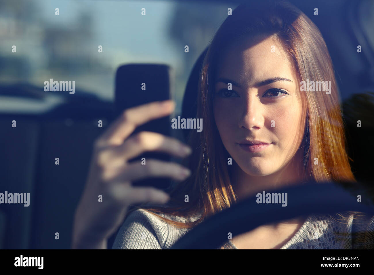 Nahaufnahme von einer Vorderansicht einer Frau Autofahren und tippen auf ein smart phone Stockfoto