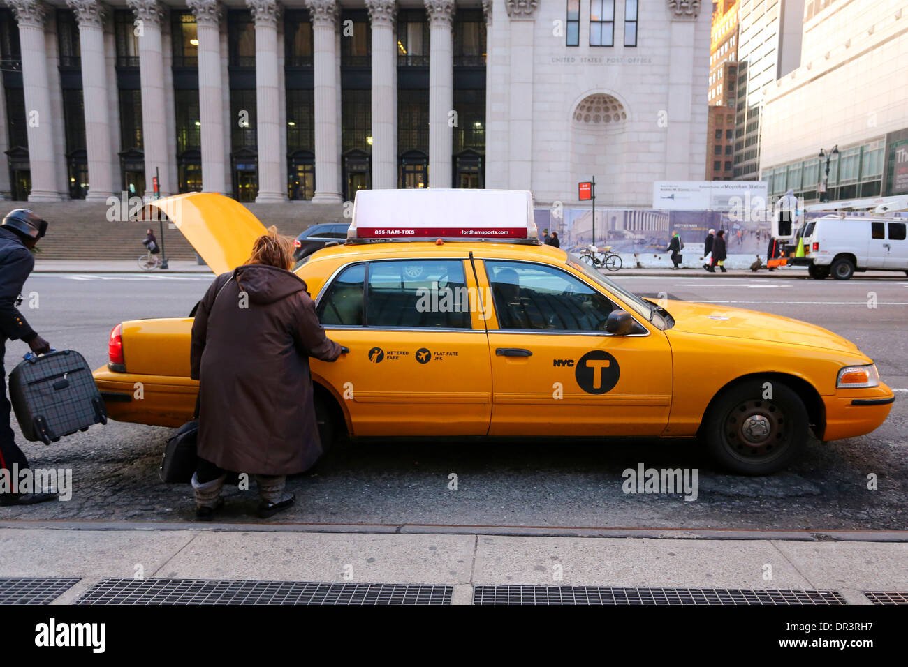Eine Person, die vor der Penn Station in New York City in ein Taxi steigt, der Fahrer, der Gepäck in den Truck des Fahrerhauses bringt Stockfoto