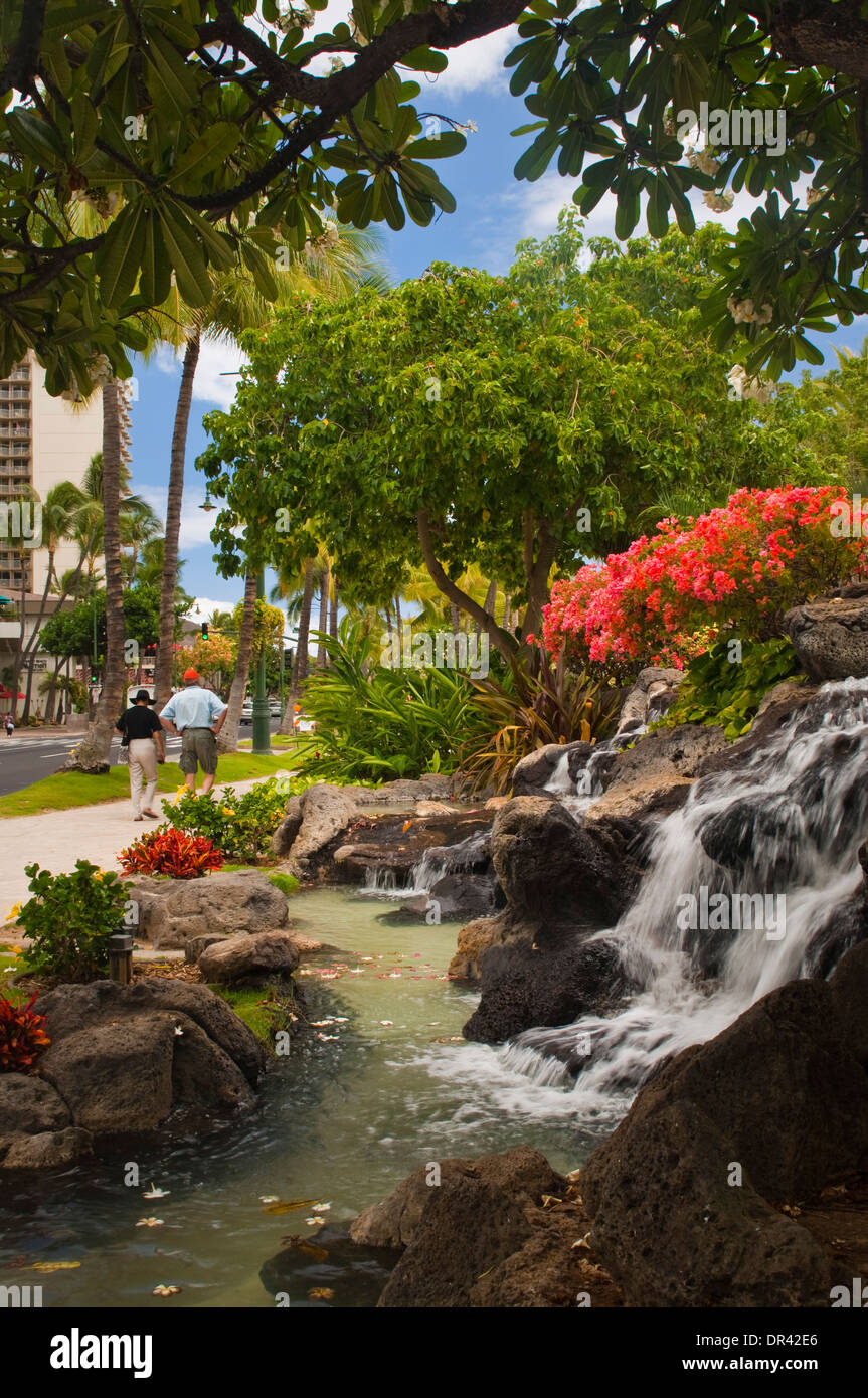 Blumen und Wasserfall Brunnen am Kuhio Beach Park, Waikiki Beach, Honolulu, Oahu, Hawaii Stockfoto