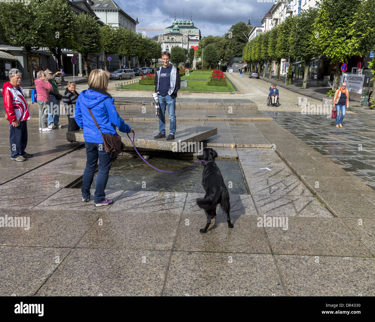 Frau mit Hund beobachten Mann auf einem konkreten Sockel Ole Bulls Plass Bergen Norwegen Stockfoto