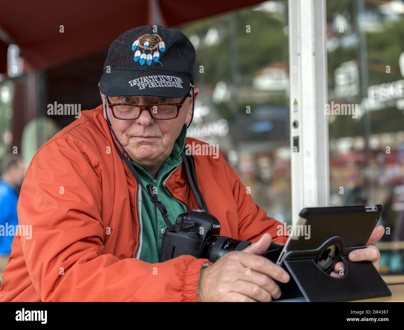 Ältere Mann mit seinem iPad und Kamera Blick fragend auf den Betrachter Stockfoto