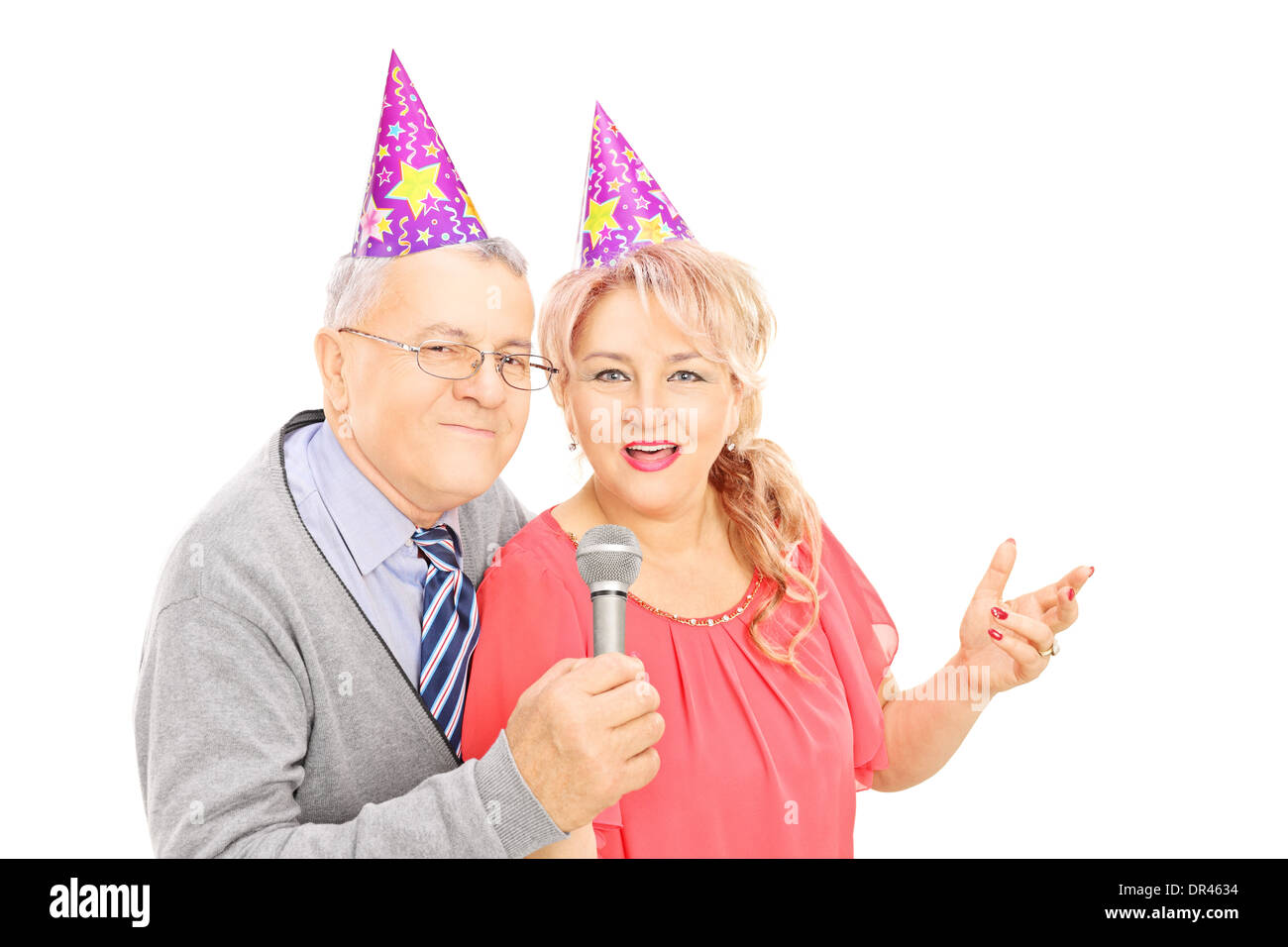 Applying paar mit Partyhüte auf Mikrofon singen Stockfoto
