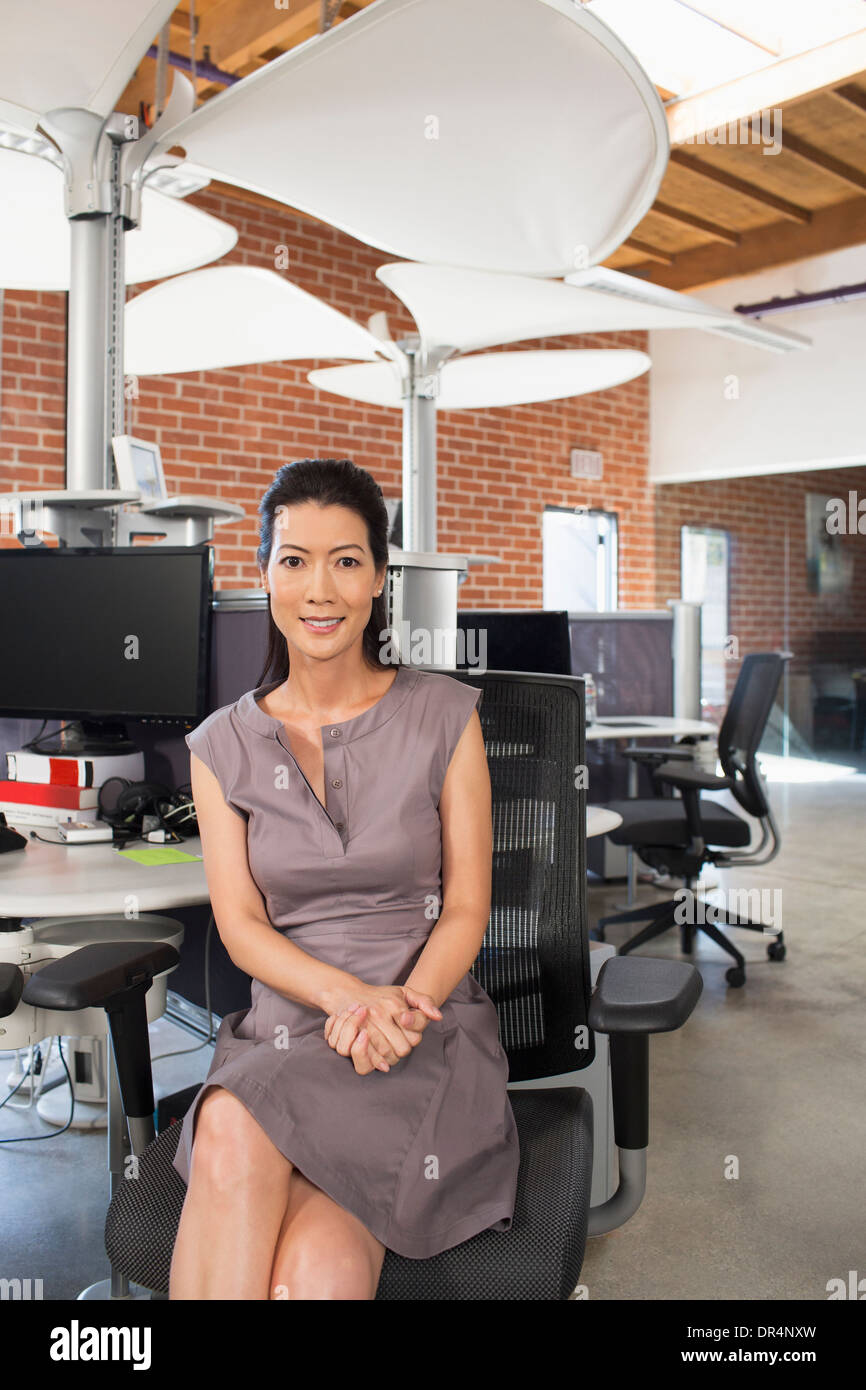 Chinesische Unternehmerin, die lächelnd im Büro Stockfoto