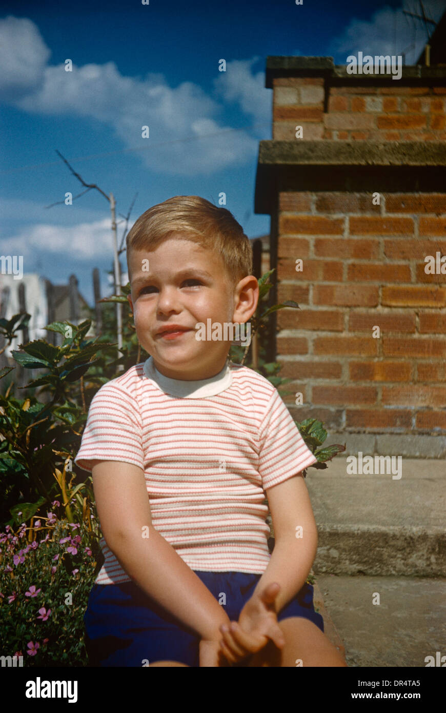 Ein kleiner Junge von etwa 5 Jahren sitzt in der Familie Garten hinter