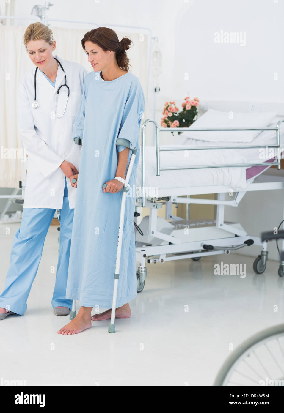 Voller Länge eines Arztes hilft Patienten in Krücken Stockfoto