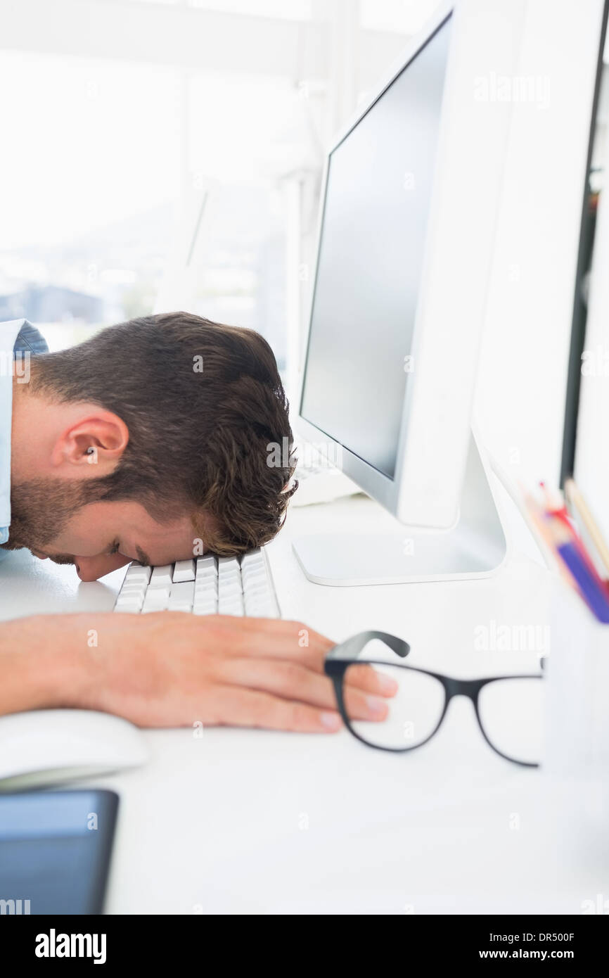 Männliche Künstler mit Kopf ruht auf Tastatur Stockfoto