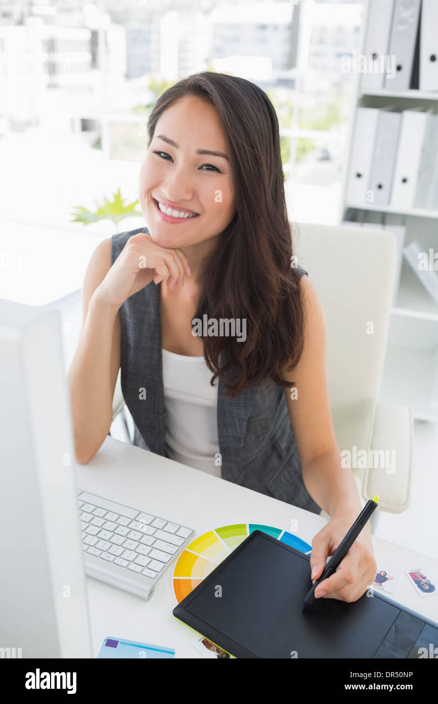 Lächelnde lässig weibliche Bildbearbeitung mit Grafiktablett Stockfoto