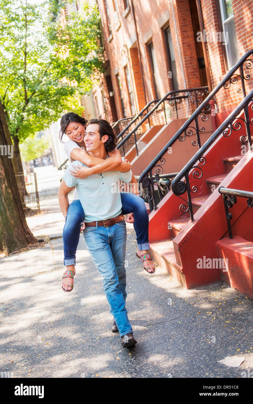 Mann mit Freundin Huckepack auf städtischen Bürgersteig Stockfoto