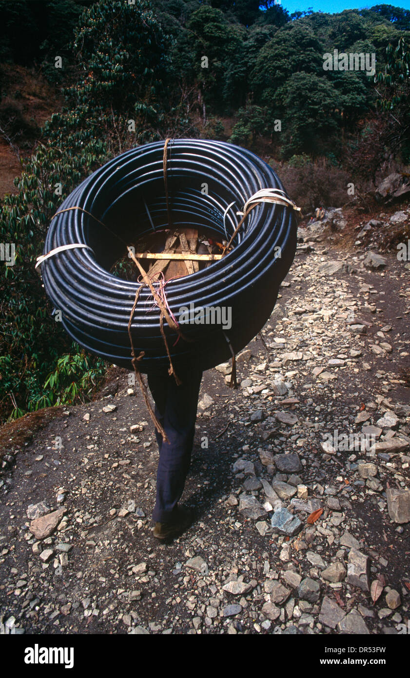 Eine Mann trägt elektrische Verkabelung bergauf auf die Annapurna Sanctuary trekking-Route in Zentral-Nepal. Stockfoto