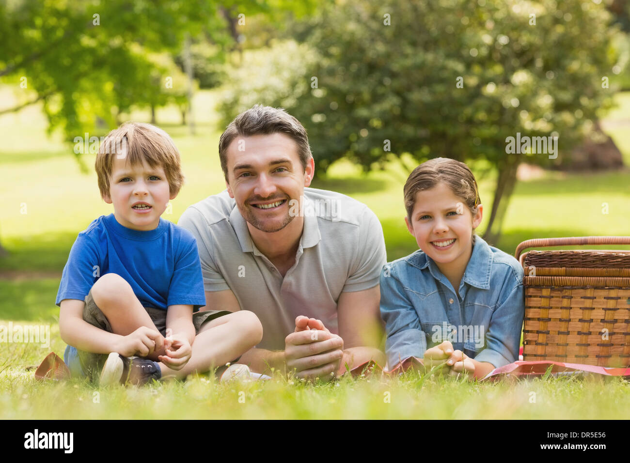 Lächelnden Vater mit kleinen Kindern liegen auf dem Rasen im park Stockfoto
